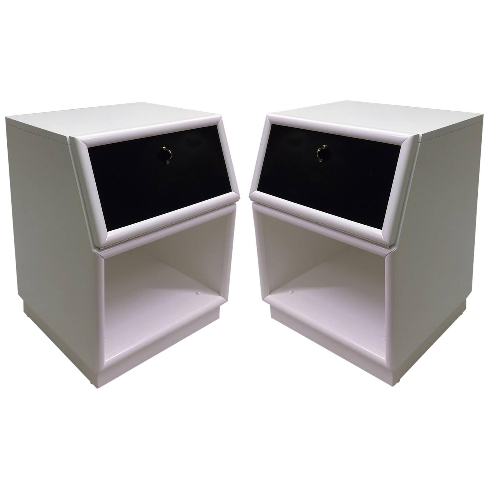 This matching pair of white lacquer nightstands features a black lacquer drop-front surface, which also provides storage when closed. Each unit has a black enamel and brass knob. They are well crafted by an excellent manufacturer named Henredon.
