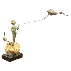 Niño volando una cometa Escultura de bronce sobre roca volcánica de Malcolm Moran