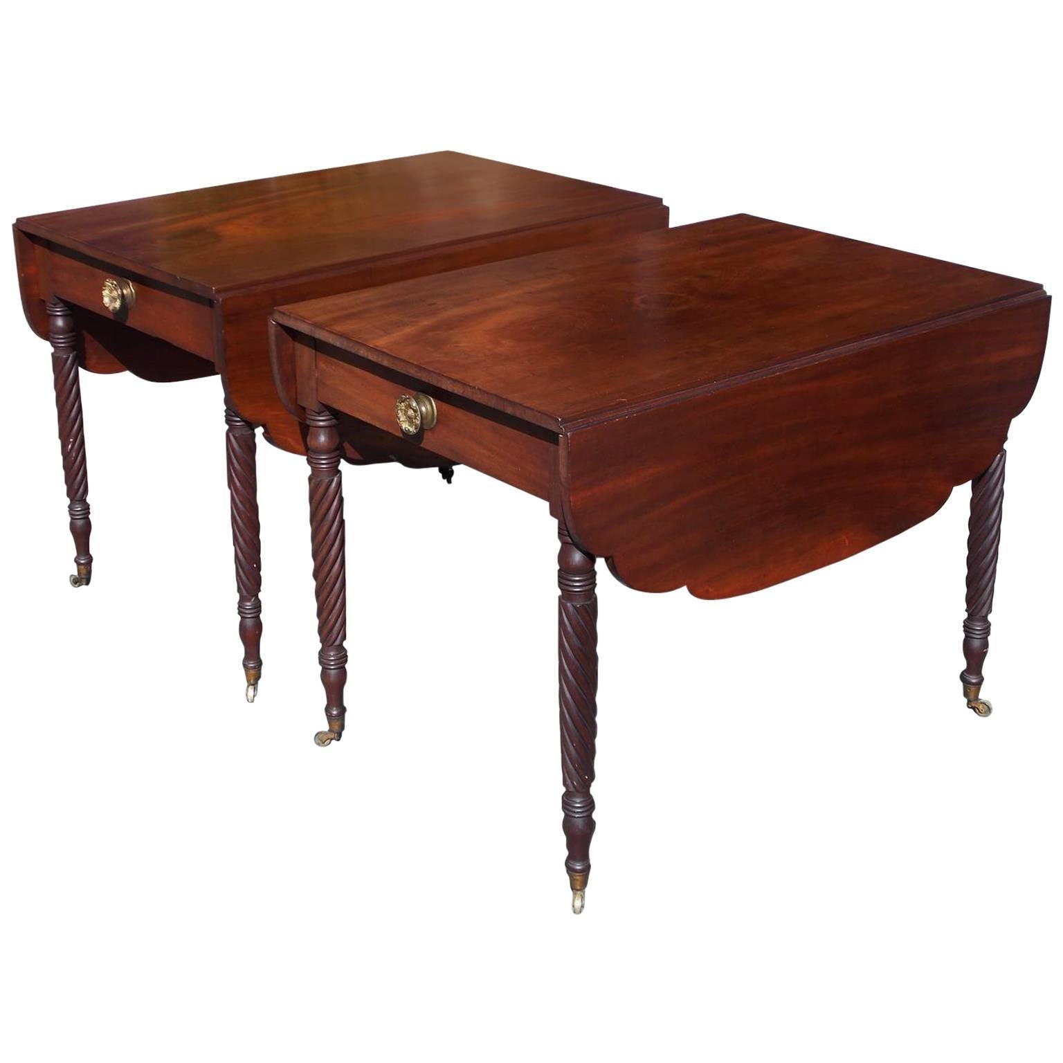 Pair of American Sheraton mahogany one-drawer drop-leaf Pembroke tables with carved scalloped leaves, original floral brasses, and terminating on turned ringed barley twist legs with the original brass casters. Baltimore, Early 19th century.