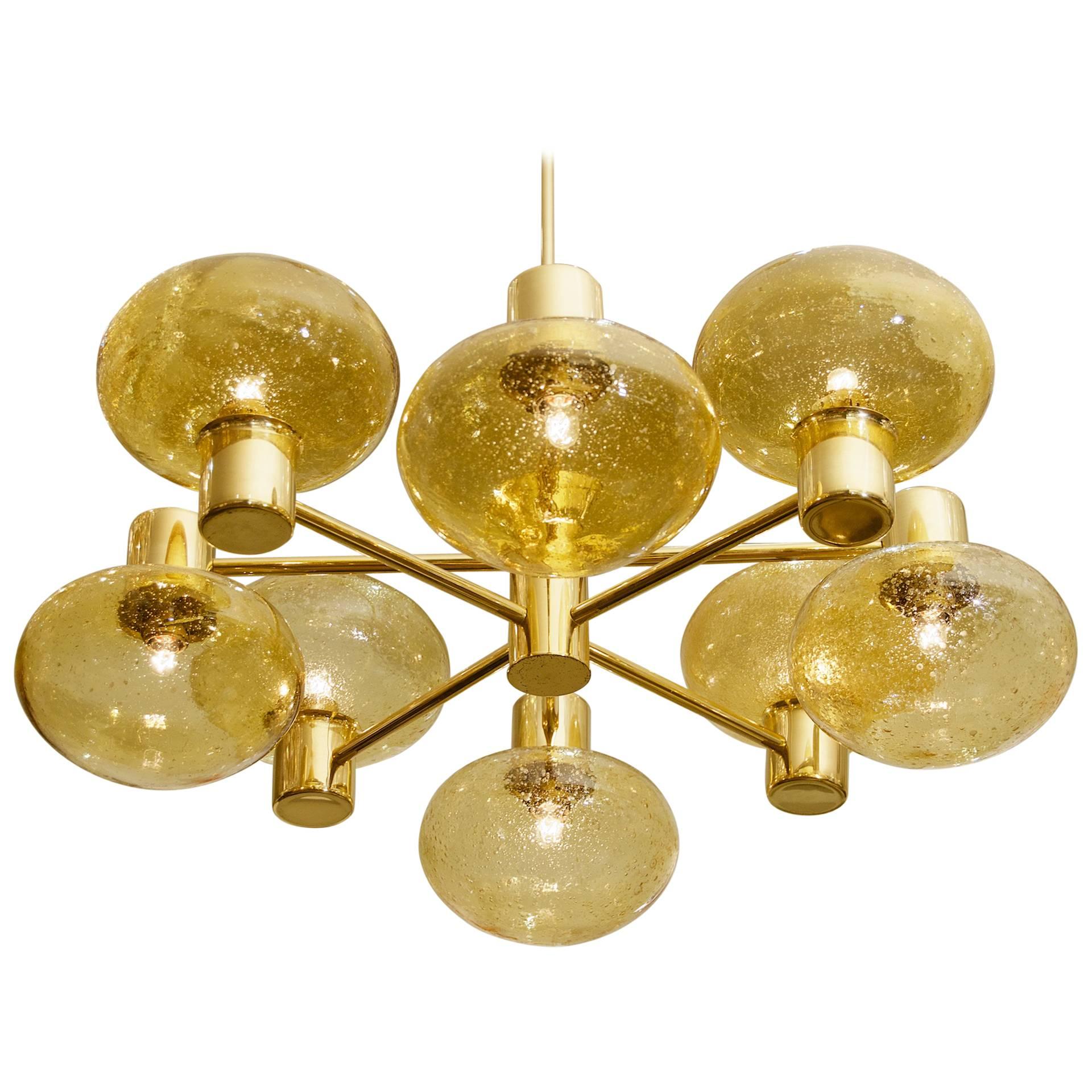 An elegant brass chandelier with two tiers comprised of four arms radiating from a central body, at the end of each arm is a blown glass amber globe, certain to add warmth to any room. 

Takes eight E-14 base bulbs up to 40 watts per bulb.