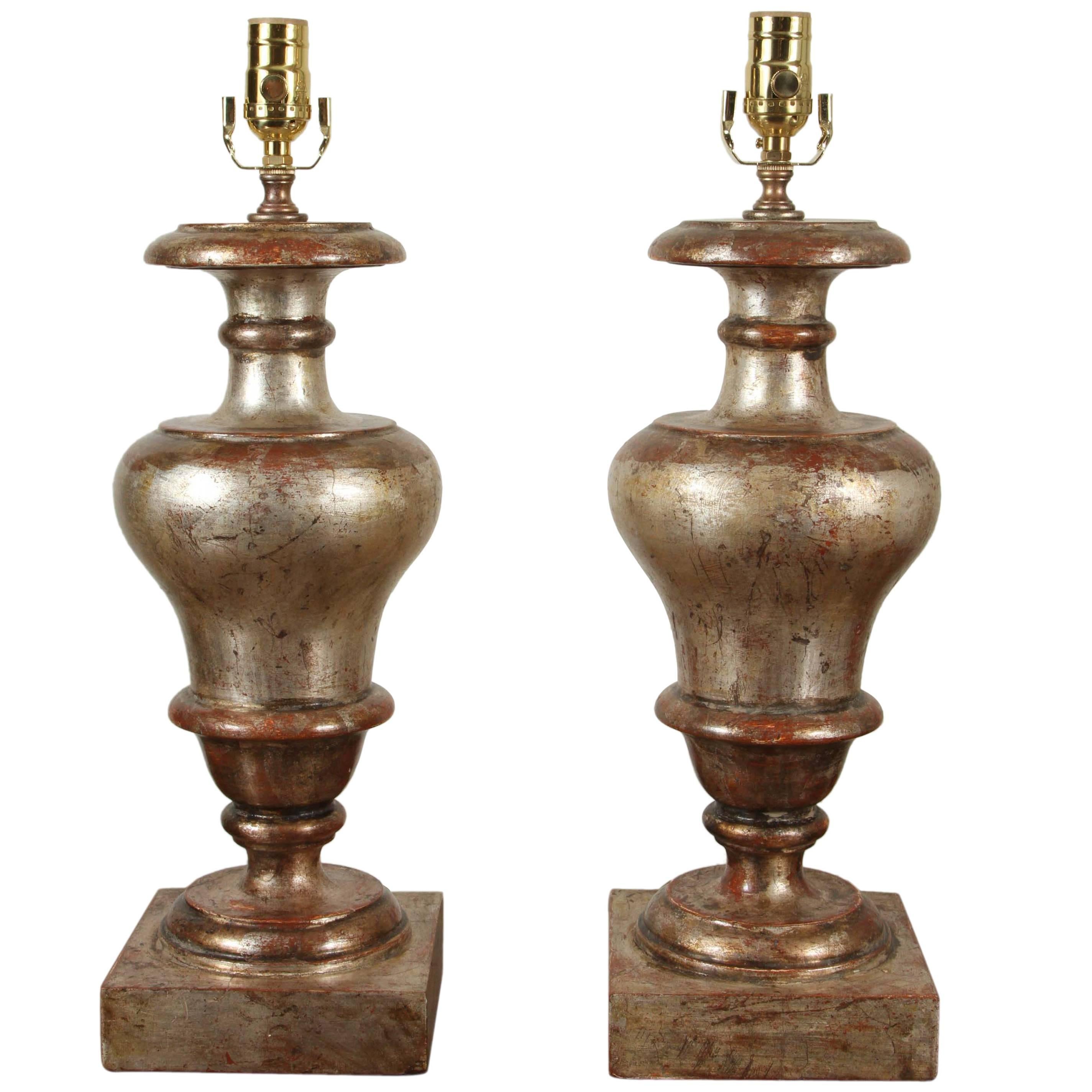 Paire de lampes de table en forme d'urne en bois sculpté et doré à l'argent, originaires d'Italie.  Les abat-jour en lin ont un diamètre de 17