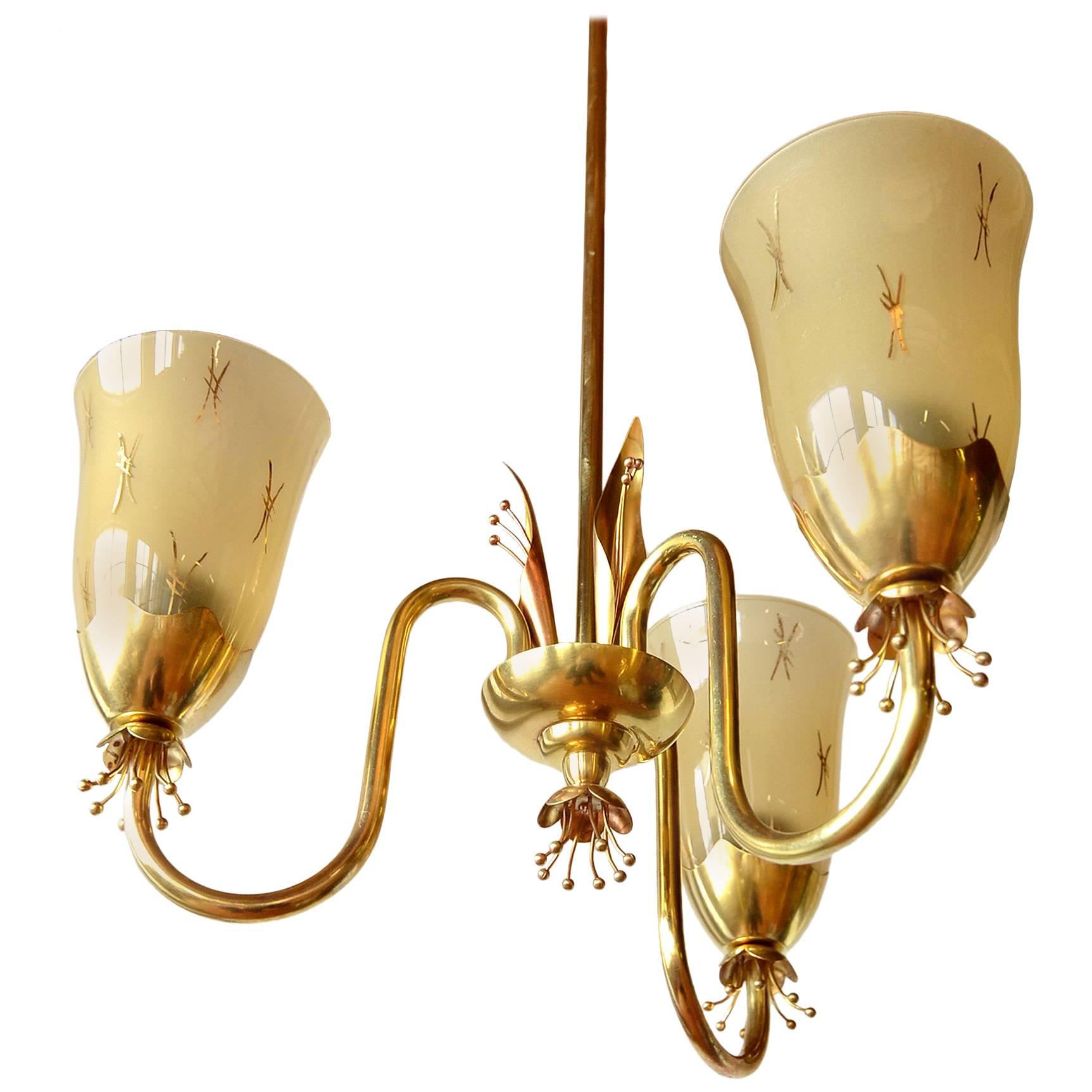 A stunning solid brass and frosted glass chandelier by Paavo Tynell for Idman, circa 1955.

This example has an incredibly bright finish. Resembles a gilded brass.

Beautiful executed handmade solid brass flower drops and spiral