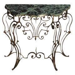 Tavolo da console in acciaio battuto con piano in marmo variegato, opera di Gilbert Poillerat