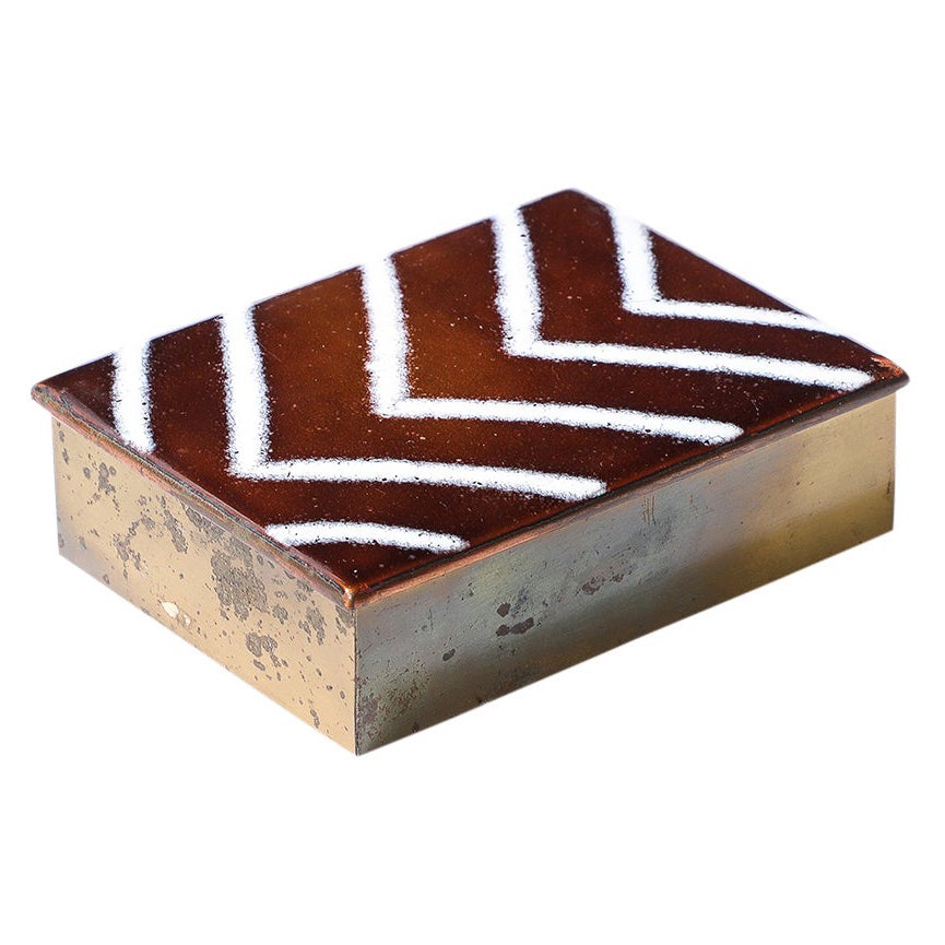 Caja de Edward Winter, esmalte, latón, con bisagra, Escuela de Cleveland, firmada. Caja con bisagras de latón a pequeña escala, con la parte superior esmaltada y decorada con un motivo de chevrones blancos sobre un fondo esmaltado de cobre oscuro.