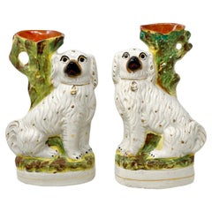 Pareja de antiguos Spaniels sentados de porcelana inglesa de Staffordshire con jarrones, ca 1890