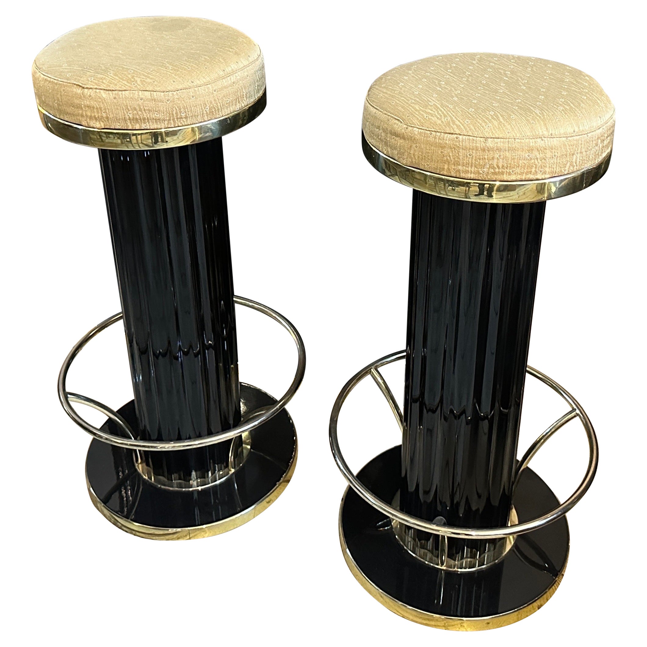 A 1960s Mid-Century Modern Italian bar cabinet paired with two matching stools. The bar cabinet is sleek and sophisticated, embodying the Italian modernist style of the 1960s. It features a glossy black lacquered surface, accented with brass trim