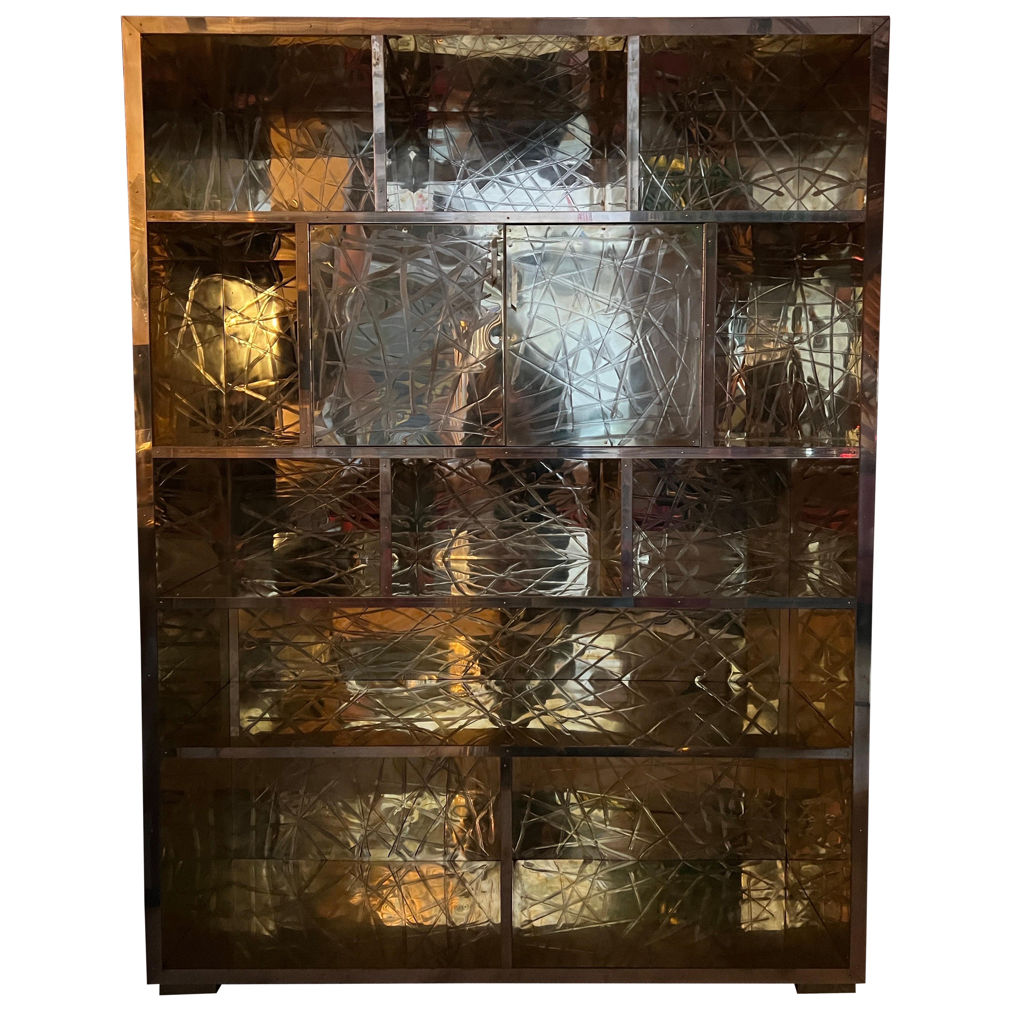 Libreria in ottone graffiato con mobile bar a specchio progettata da Pandora Decor.
L'ottone graffiato copre tutto il corpo del mobile, compresi i lati e il piano.
Il mobile bar con specchio si trova all'interno delle porte centrali.