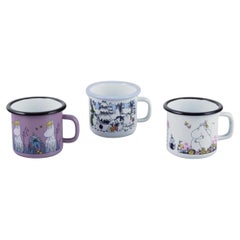 Muurla, Finland. Three enamel mugs with motifs from the Moomin stories