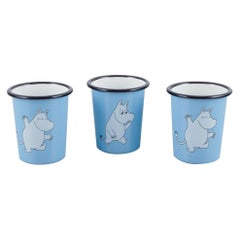 Muurla, Finland. Three enamel mugs featuring motifs of Moomin trolls.