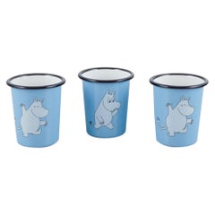 Muurla, Finland. Three enamel mugs featuring motifs of Moomin trolls.