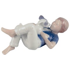 Royal Copenhagen. Figurita de porcelana de un niño con un perrito. Rara estatuilla.