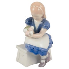 Bing & Grøndahl, Denmark. Porcelain figurine of seated girl with flowers.