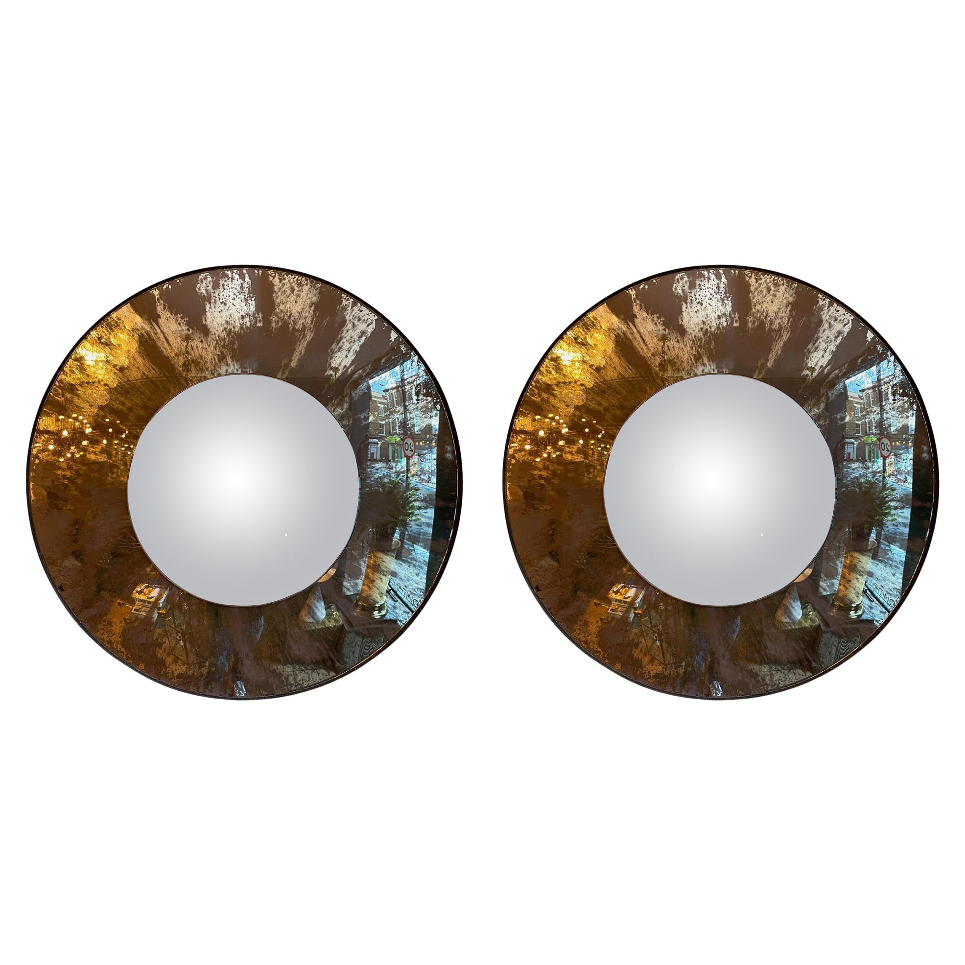 A pair of large circular convex mirror, with outer convex in very distressed silver mirror, with inner convex less distressed, with a bronze banded frame finish.