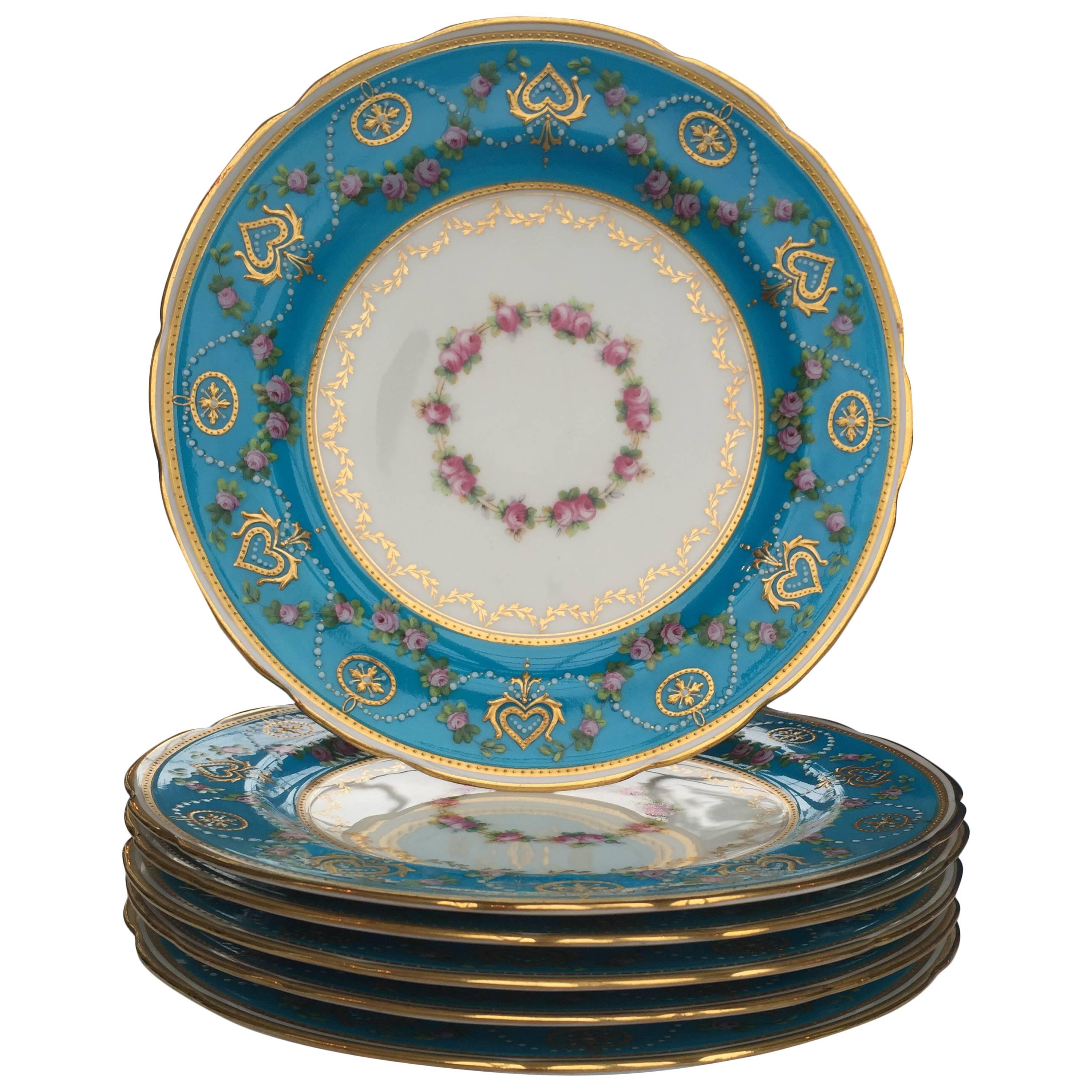 A very elegant set of Ten celeste blue bone China desert plates by Minton, fit for a Queen.
The brilliant translucent celeste blue enamel border is painted with a pearl Meander and pink rosebud swags. In the center of the Plate is a wreath of roses