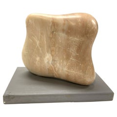 Escultura de piedra de feldespato tallada y pulida a mano sobre base de madera lacada.
