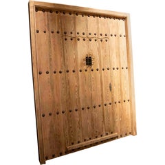 Puerta rústica española de madera de los años 50 con clavos forjados y reja central de hierro