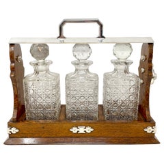 Antiguo tántalo inglés de 3 botellas de cristal y roble montado sobre plancha de plata, circa 1890