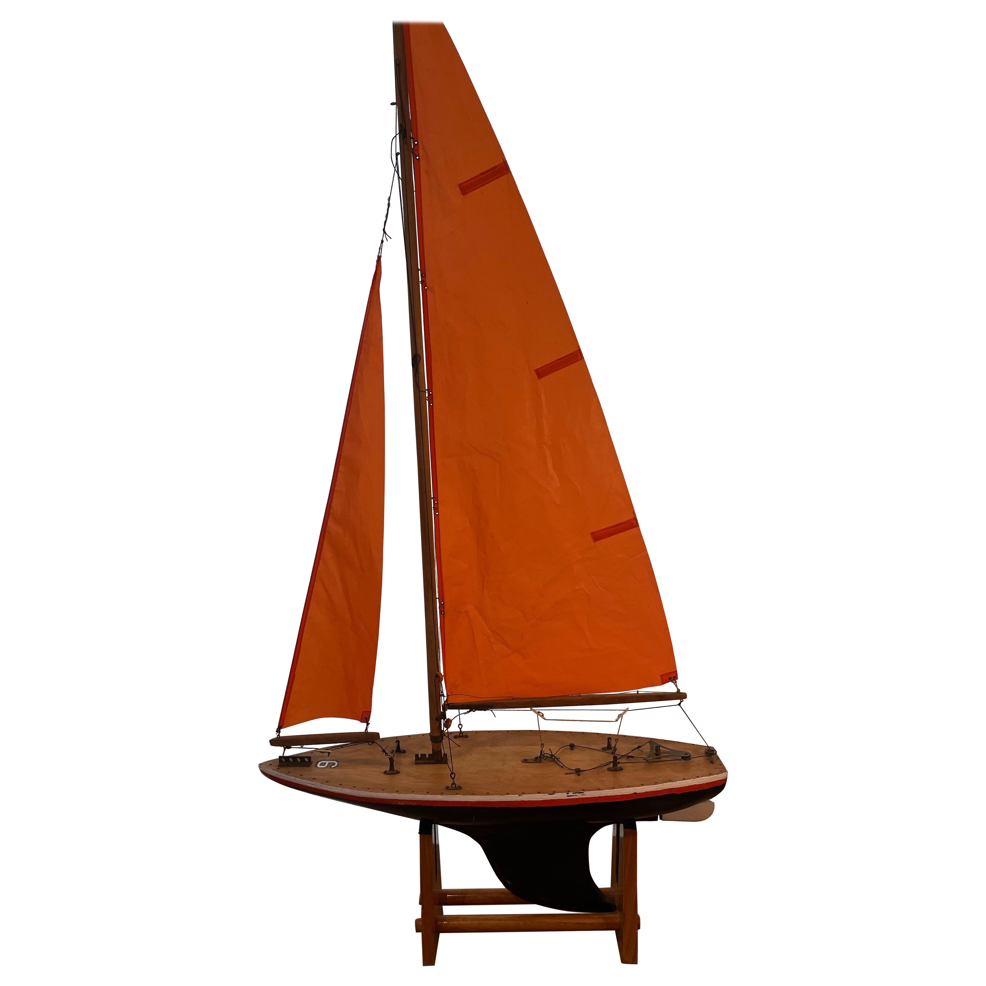 Velero artesanal de época con velas rojas, mediados del siglo XX