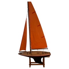 Velero artesanal de época con velas rojas, mediados del siglo XX