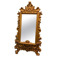 Floor mirror in gilded wood, richly carved with scroll decorations, Italy
