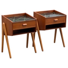 A pair of 1960´s teak nightstands with oak legs and black decorated glass top