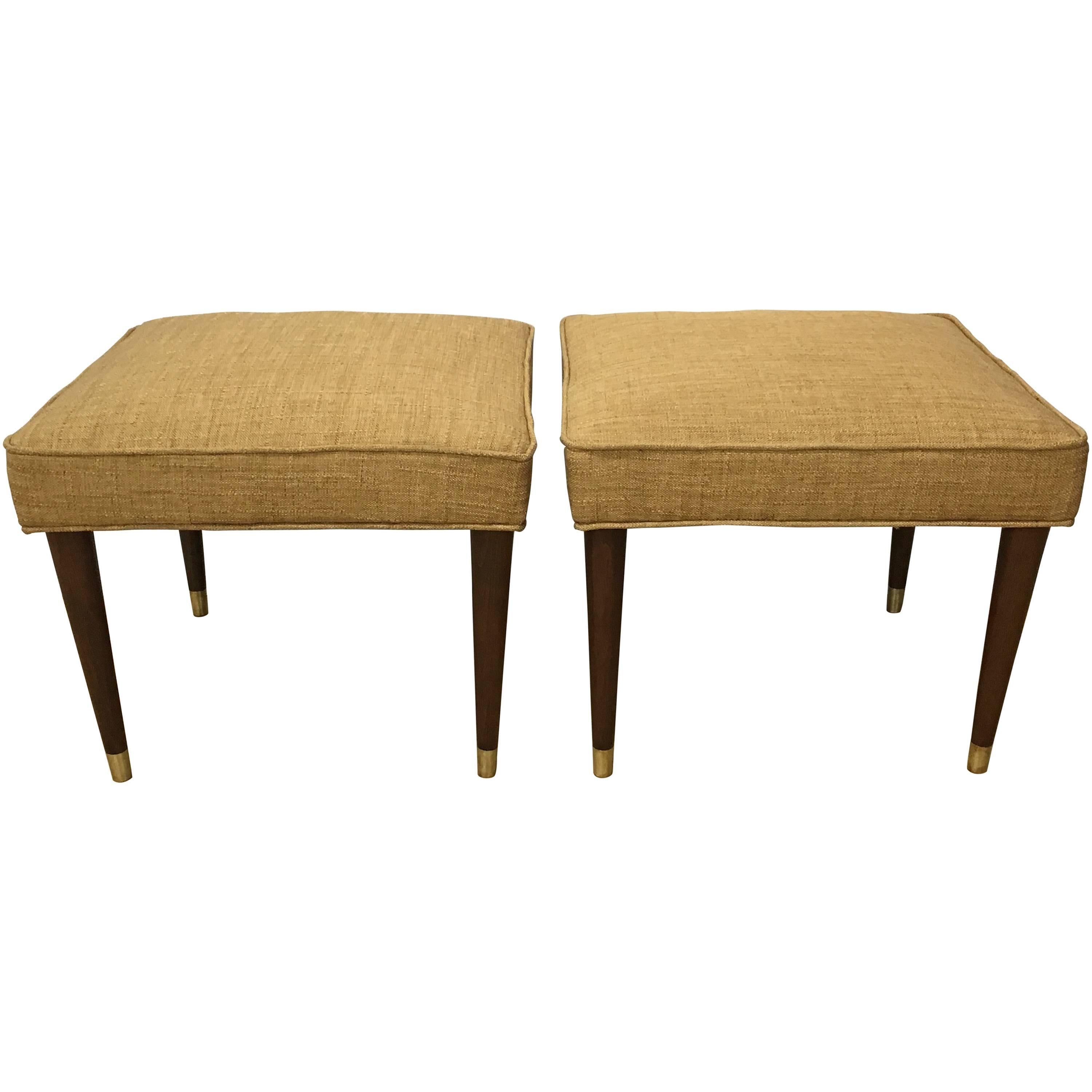 Each one of square form with upholstered seat raised on four tapering legs with brass sabots.