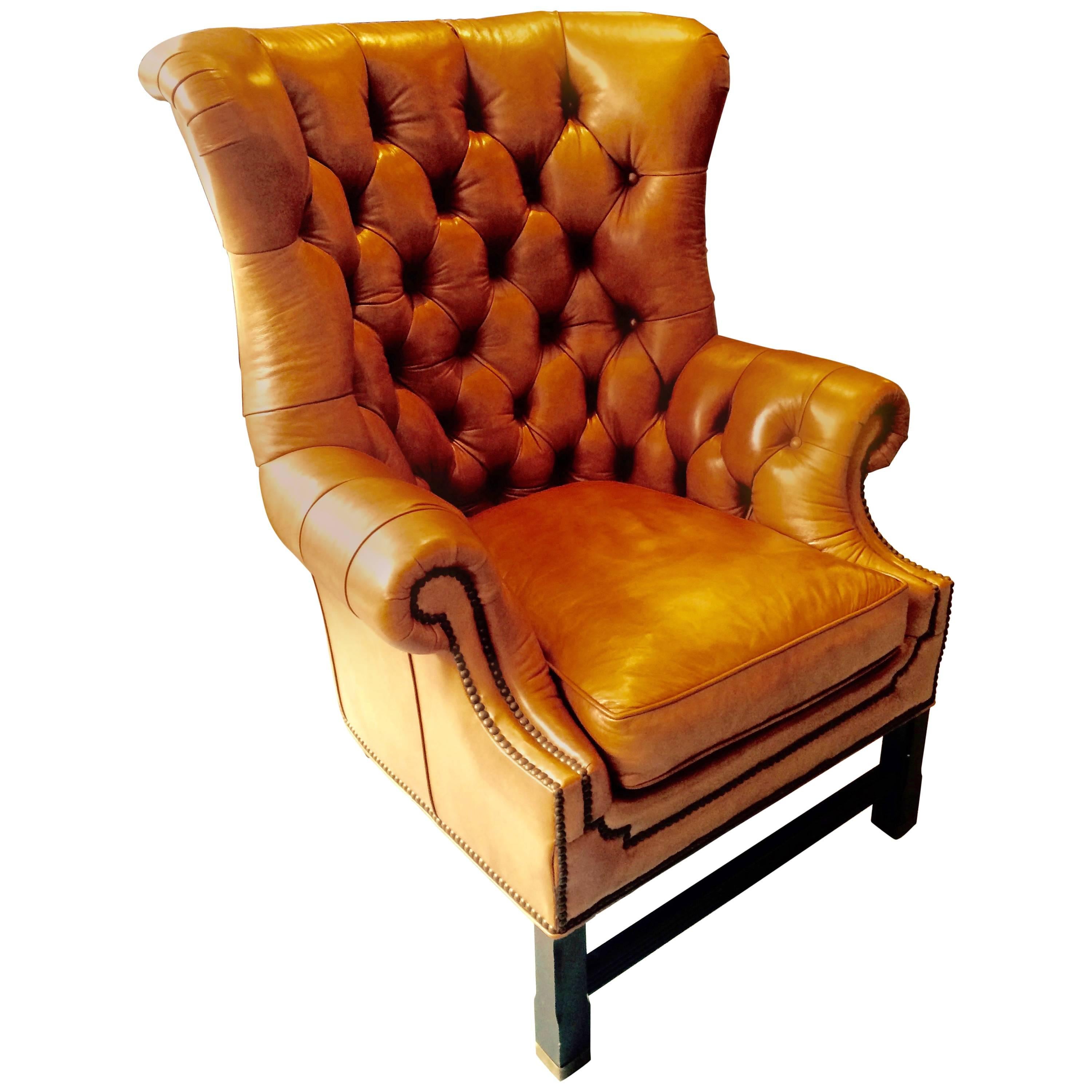 Handsome leather upholstered wing chair in wonderful shade of camel; leather tufted with nailhead trim. Feet have brushed brass caps. Made by Whittemore Sherrill. Seat depth measures: 25".
  
    