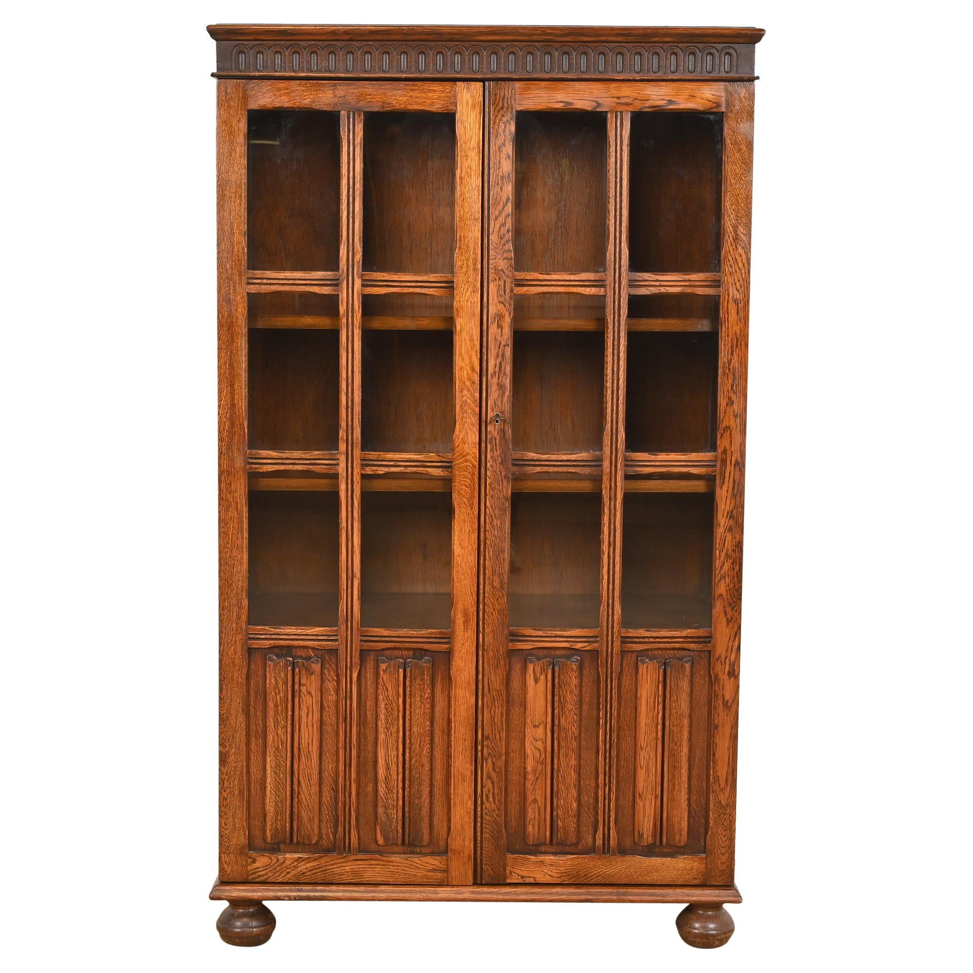 Ancienne armoire bibliothèque à façade vitrée en Oak Oak Tudor sculpté, vers 1920