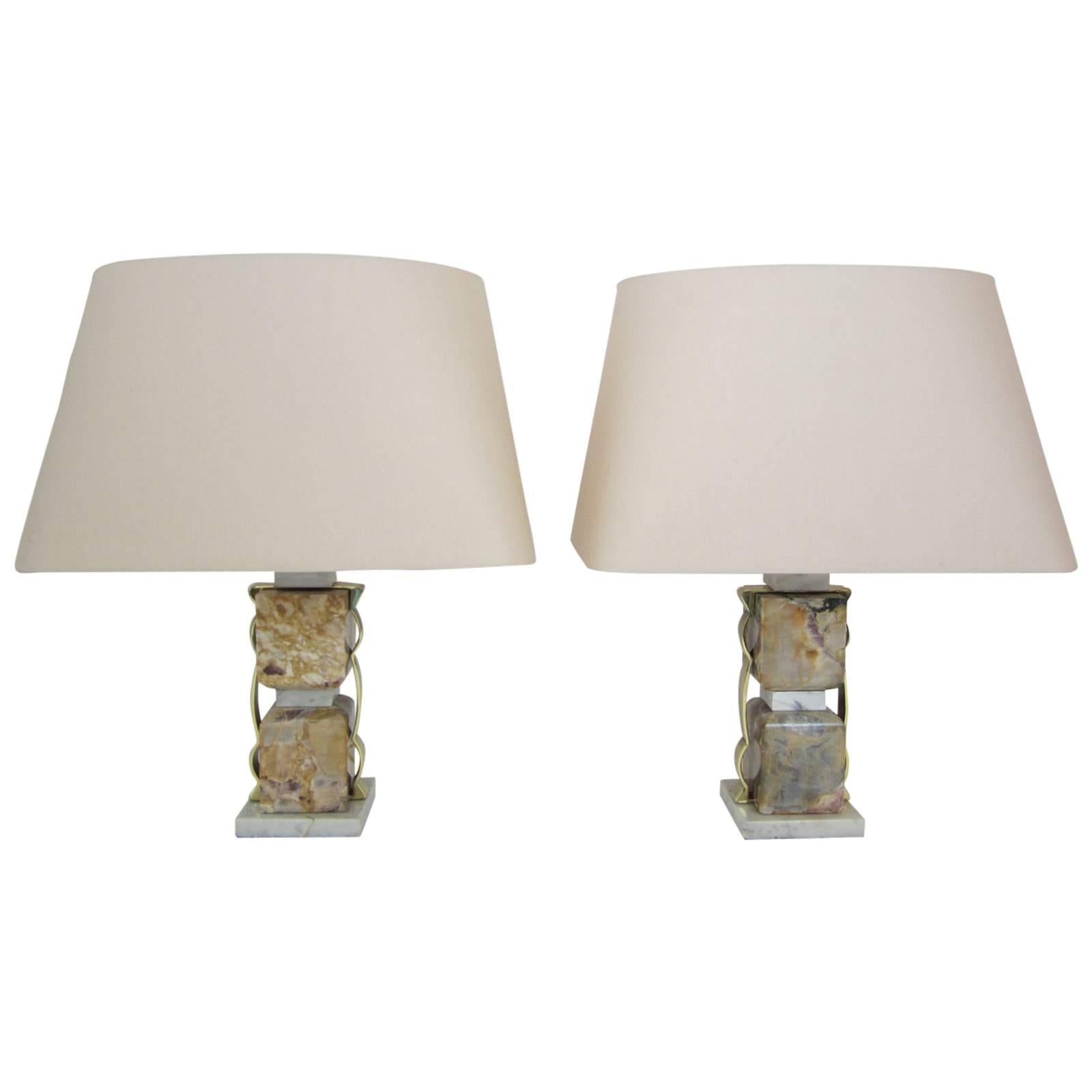 Pair of table lamps in stacked marble blocks with heavy gauge contoured brass straps that run up, across, and down each lamp. The marble has wear and one base that was broken and glued, however, these lamps have a fantastic vintage aspect to them