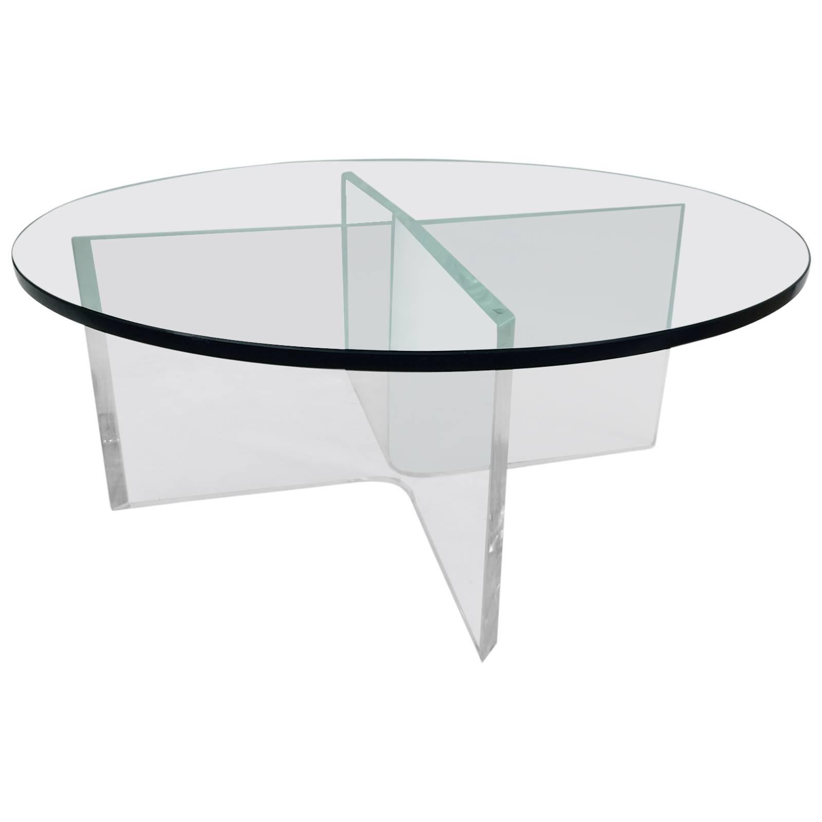 This round coffee table is composed of a glass top finished with a beveled edge and blue tint resting on a two piece bent Lucite base. The table produces great lighting effects with its reflections, refractions and shadows.