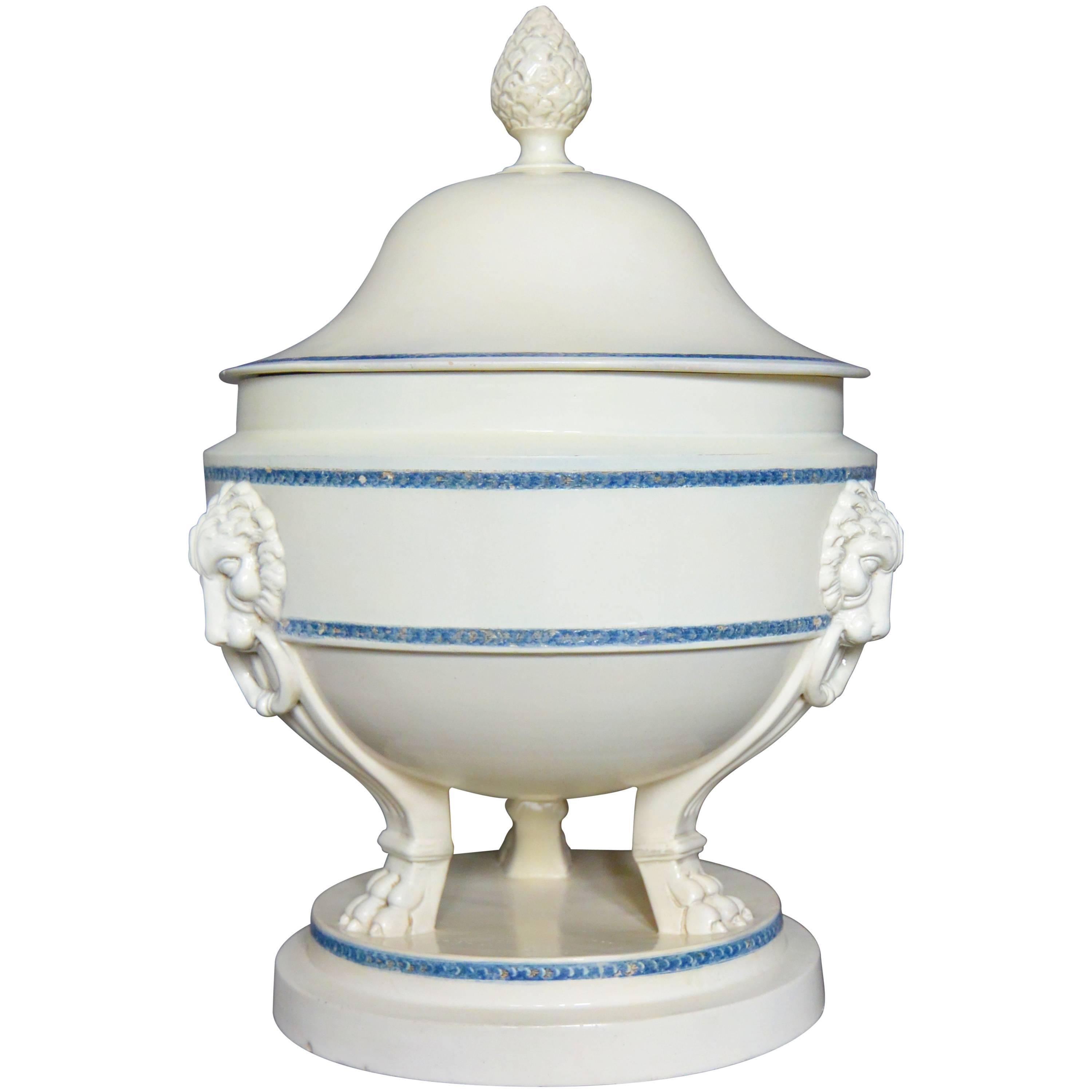 Large Neoclassical creamware tureen. Large neoclassical creamware zuppiera of tripod form with lion masks with rings supported on fluted monopedia above stepped circular base, with blue banding and pinecone knopped lid; with impressed markings for