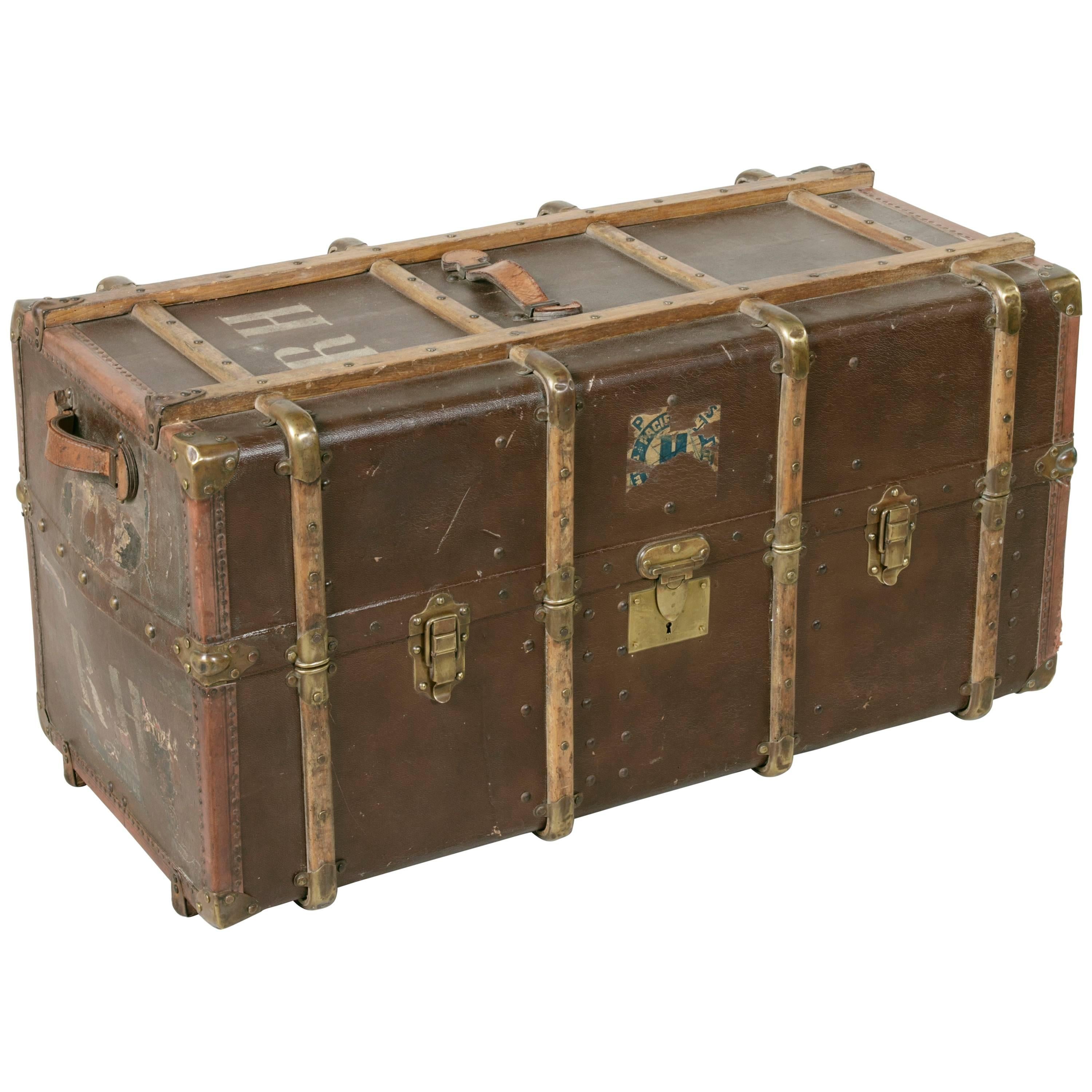 A beautiful, classic and large example of turn-of-the-century travel luggage, this antique French steam trunk features all of the quintessential details, down to its lovely aged travel sticker remnants and initials. The exterior is of a rich brown