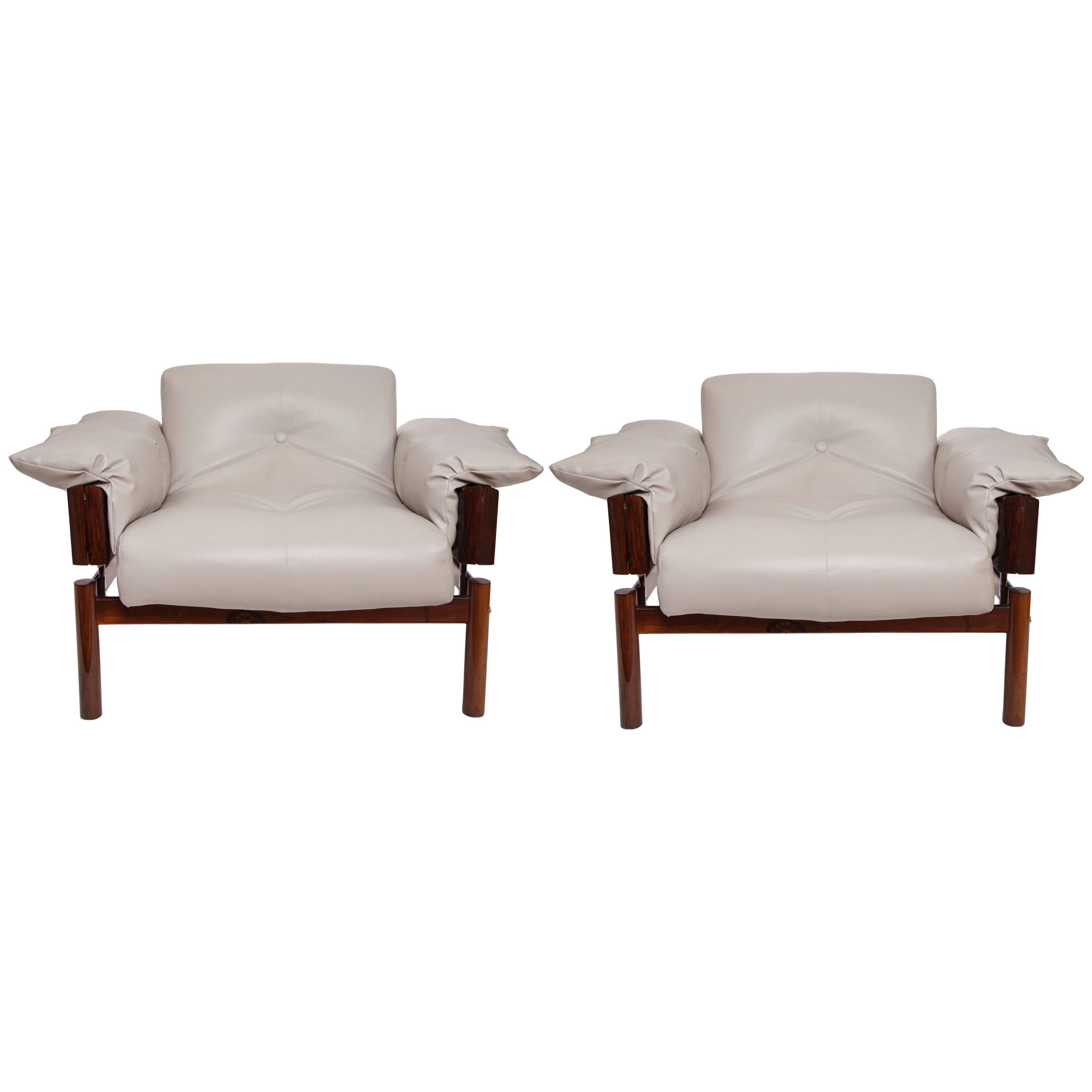 A pair of lounge armchairs by Brazilian designer Percival Lafer, produced circa 1960s, each with cushioned button-tufted back, arms and seat, upholstered in dove grey faux leather, against a linear jacaranda frame, accented with chrome. Very good