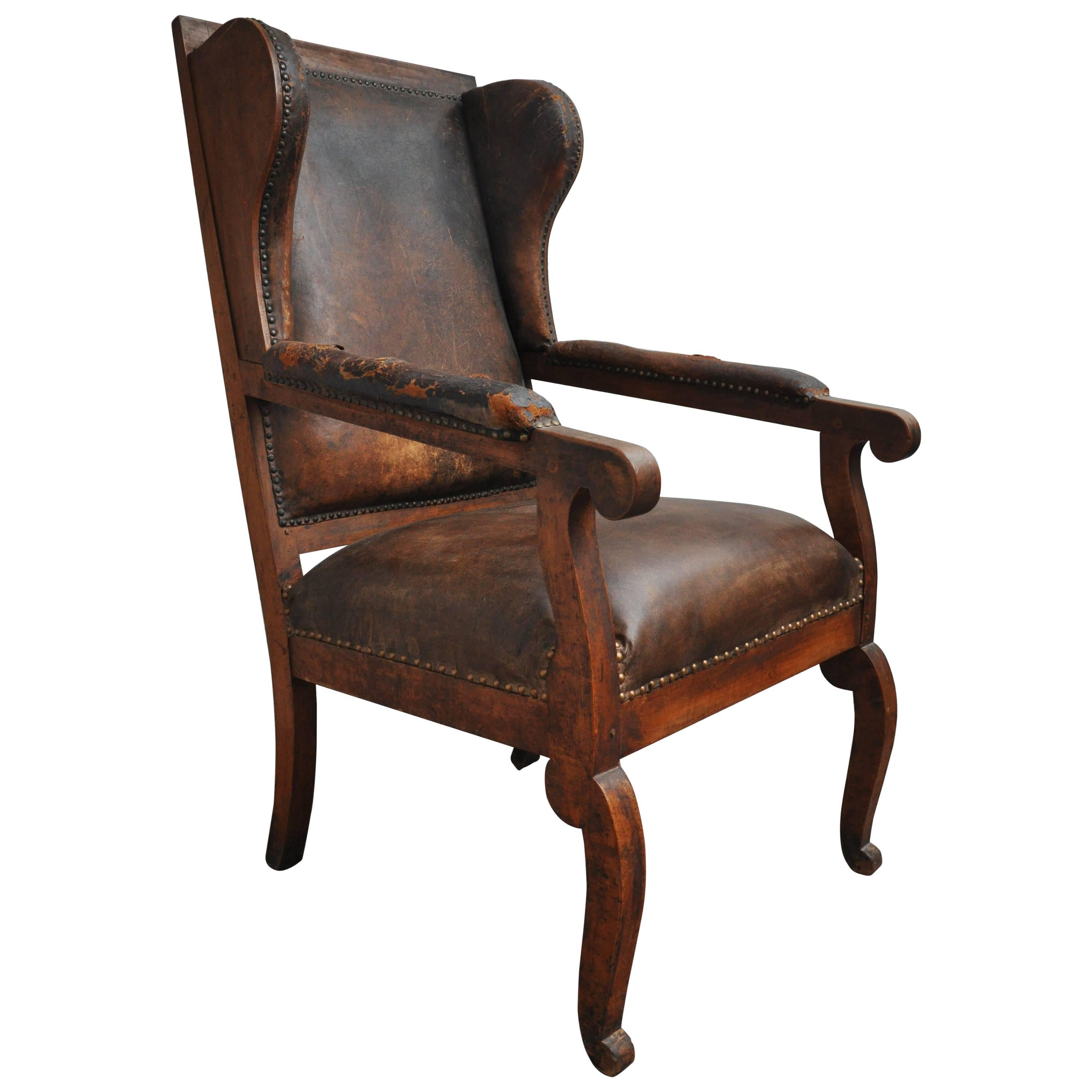 Late 19th century German Biedermeier high back wing chair.  The chair features the original antique leather arms and back (Seat recently reupholstered). Nailhead detail. Exposed wood frame and features original burlap upholstery on the back of