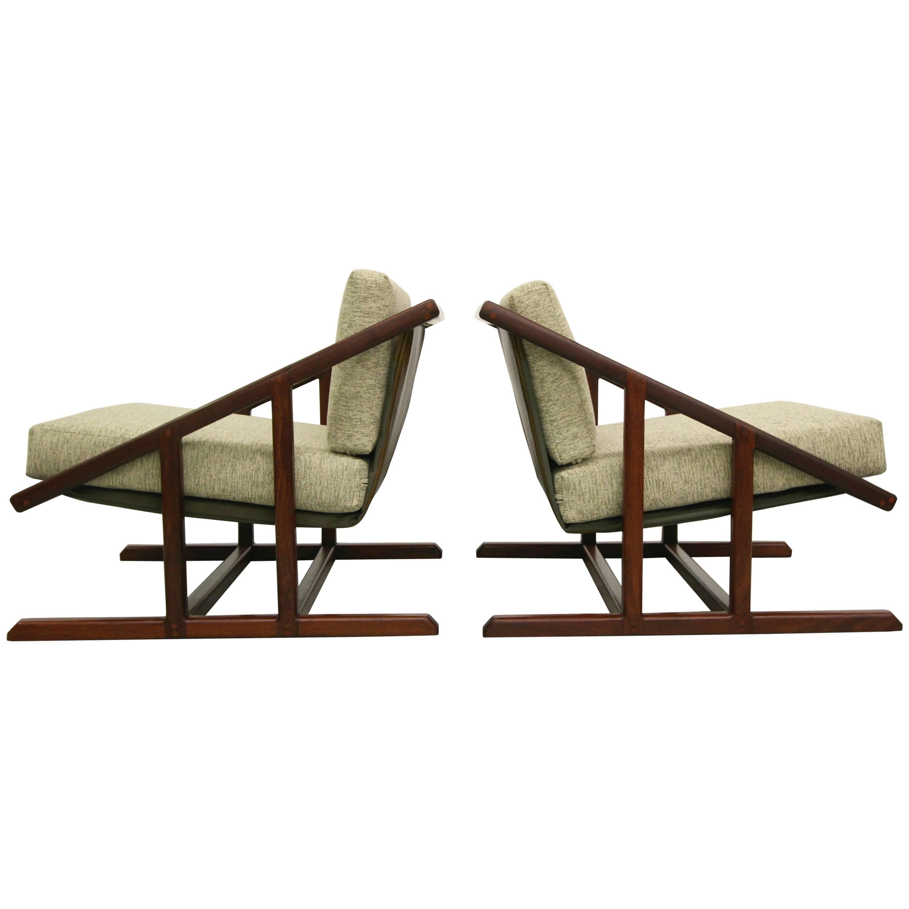 Super rare pair of angular, solid walnut sling chairs. These chairs are like no others. The lines created by their solid walnut frames create two masterpieces. These chairs feature a leather sling that supports the cushioned seating. If you're