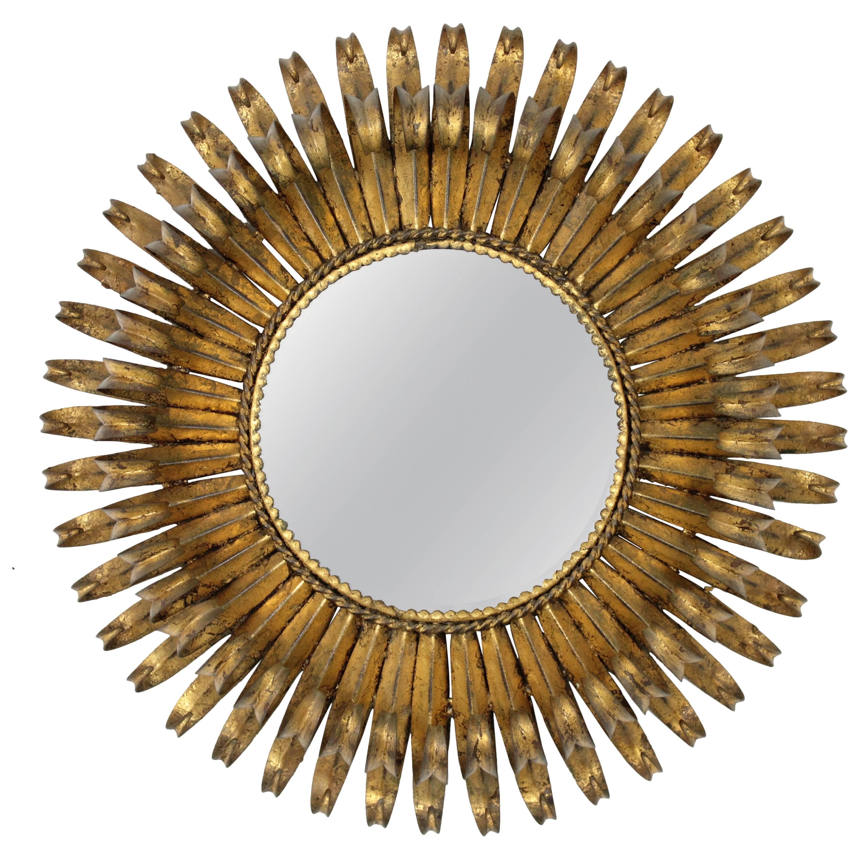 Lovely 1950s hand-hammered eyelashed gilt iron sunburst mirror with gold leaf finish and circular shape.
The frame is made by a double layer of curved beams in eyelash shape that makes the piece highly decorative. It has a beautiful original vintage