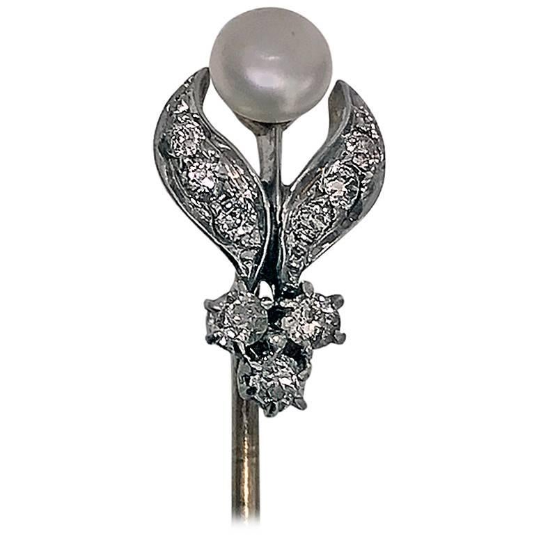Platinum, 18-karat, diamond and natural pearl stickpin, circa 1910. The stickpin in the form of an open foliate bud, set with a small silver grey button natural pearl, gauging approximately 4.8 mm, the foliate surround set with nine small old mine