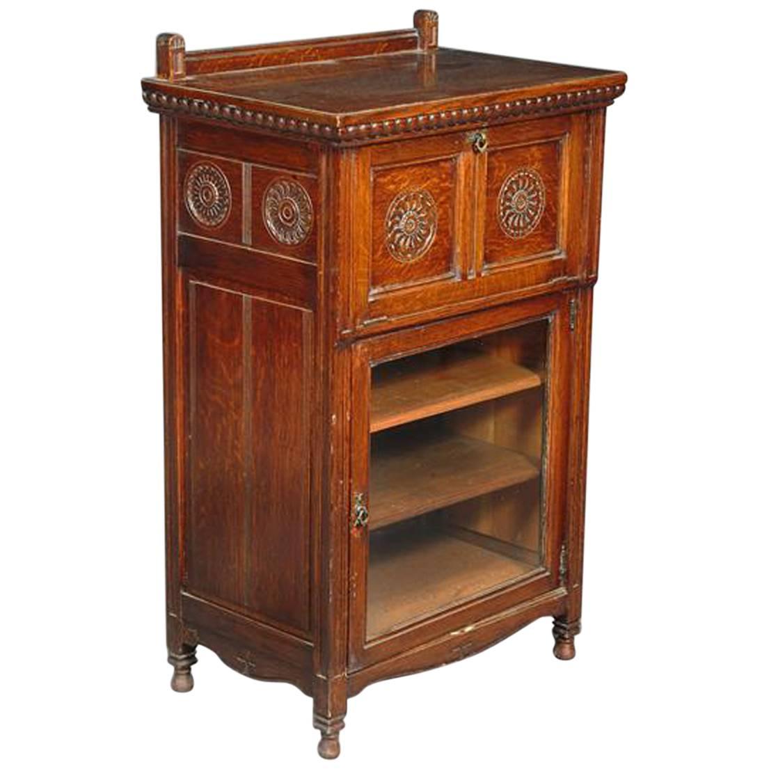 A Gothic Revival Carved Oak Glazed Music Cabinet, designed by B Talbert