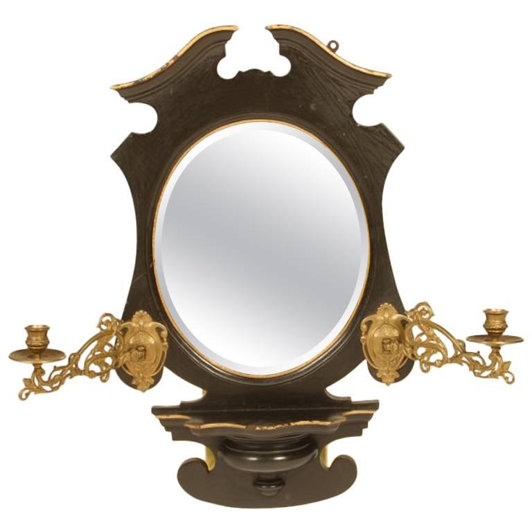 An Aesthetic Movement Ebonized and Gilt Mirror with Brass Candle Sconces