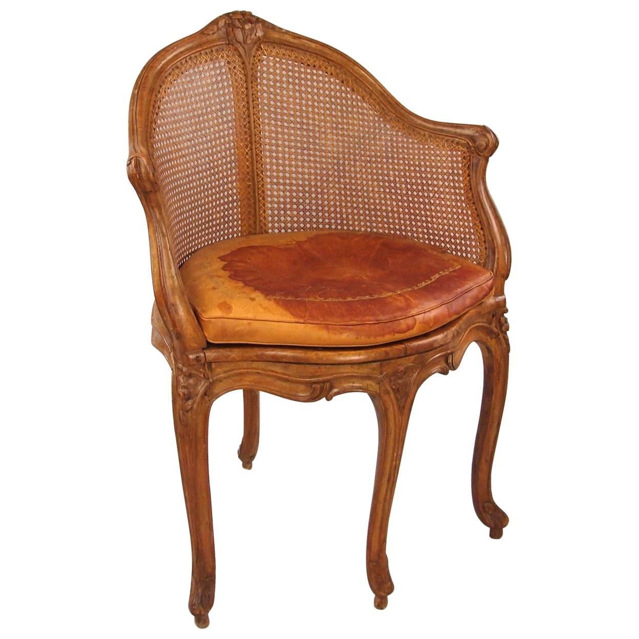 A good 18th century Louis XV period walnut caned fauteuil en bureau with a distressed leather cushion, circa 1760.
