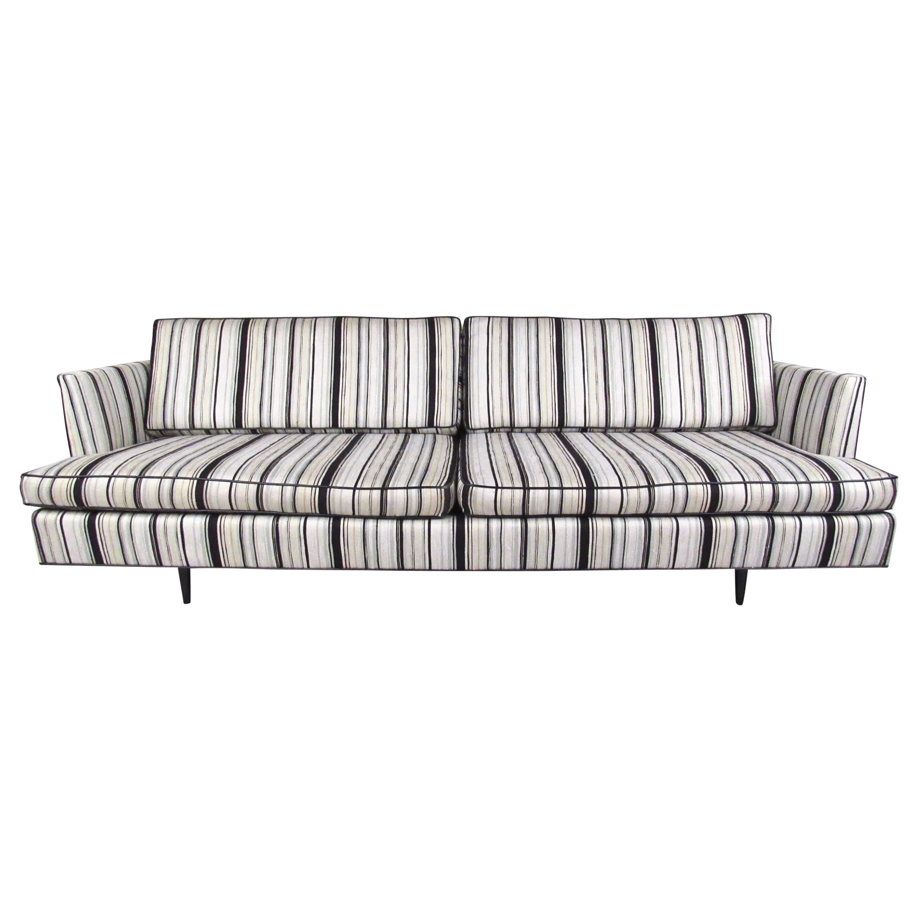 Ce spacieux canapé de style Dunbar est doté de profondes assises rembourrées avec un tissu rayé vintage unique. Les accoudoirs découpés et le design bien proportionné ajoutent à l'attrait du milieu du siècle de ce grand canapé, ce qui en fait un