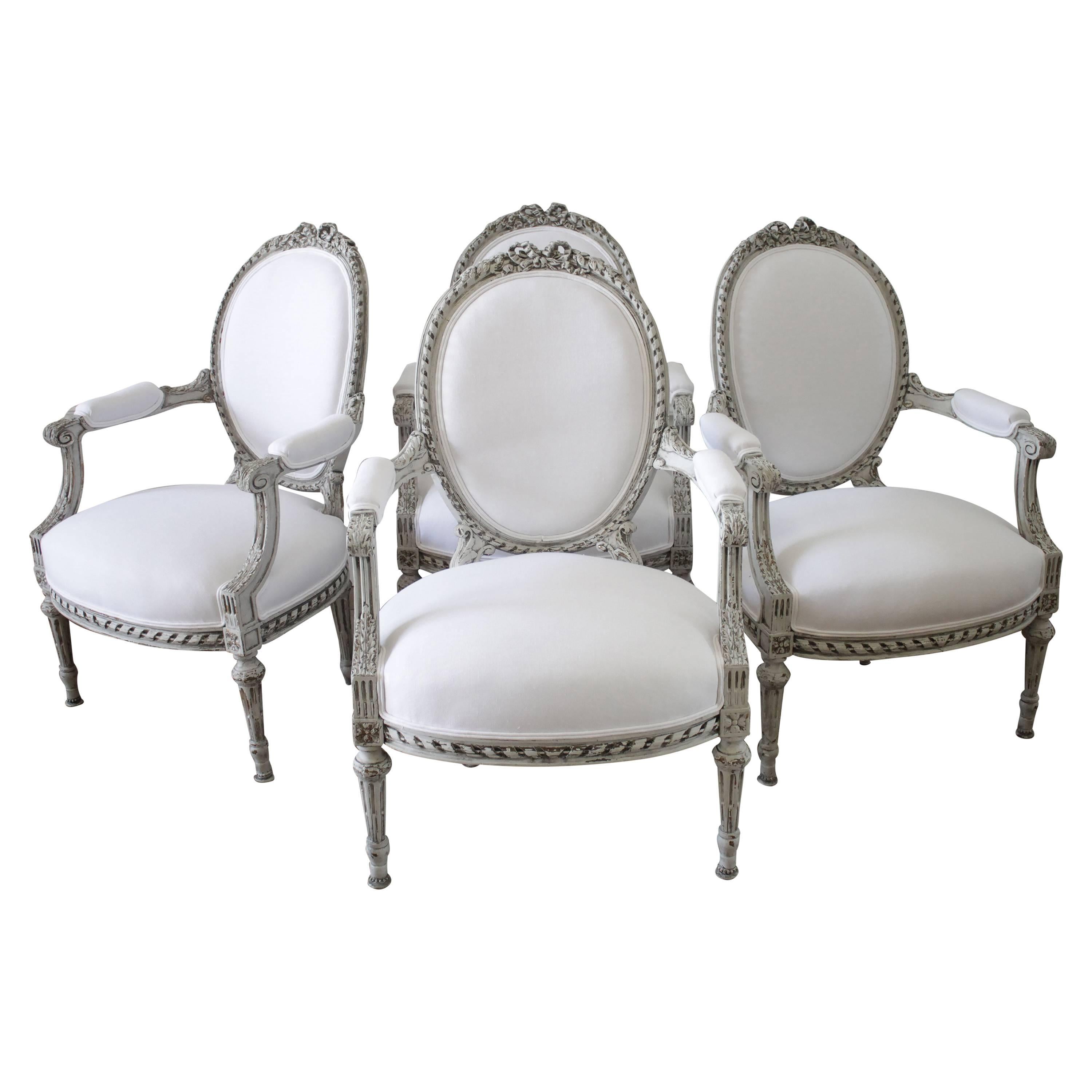 Four Painted and White Linen Upholstered Louis XVI Ribbon Carved Armchairs