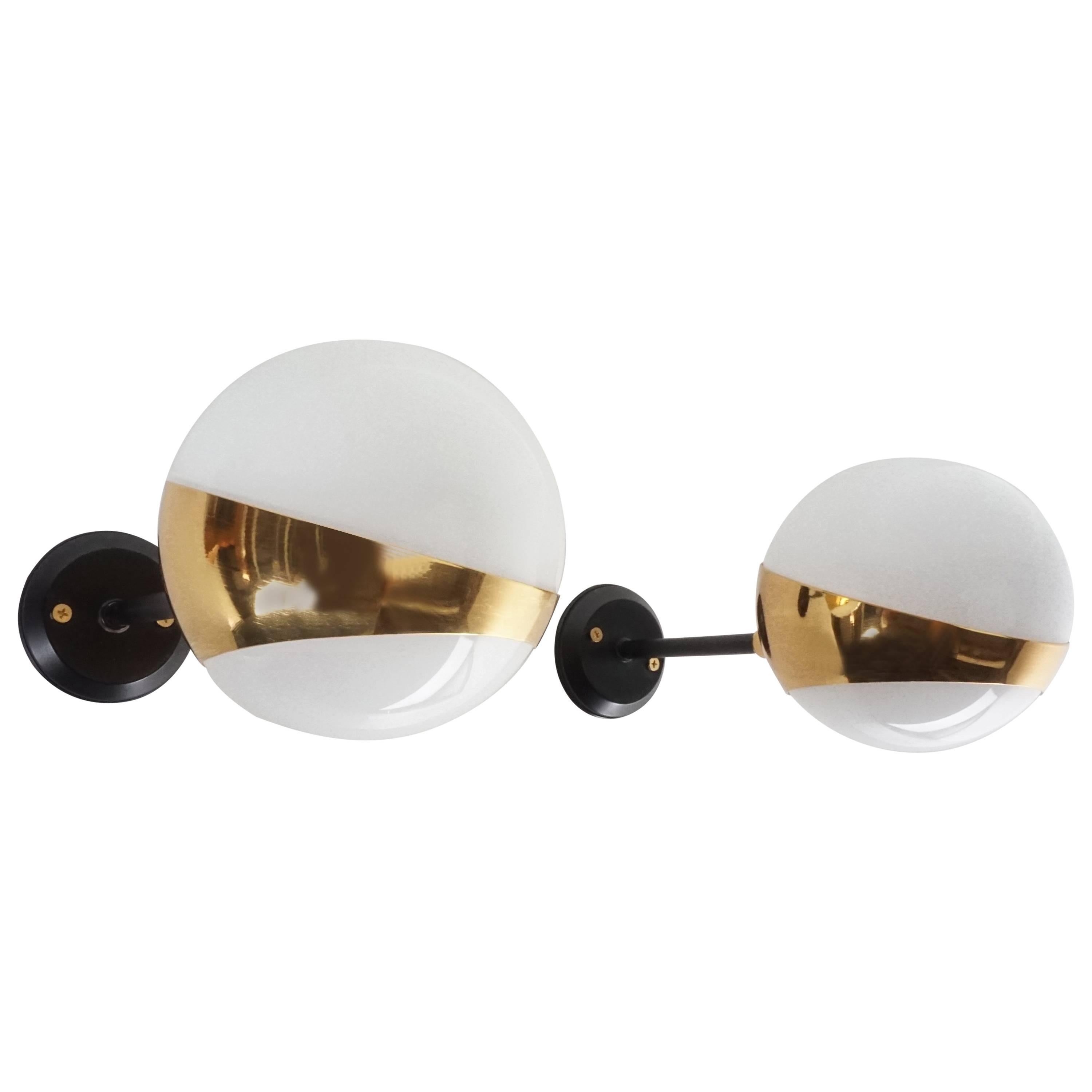 Articulating pair of globe sconces with brass and black details.
 