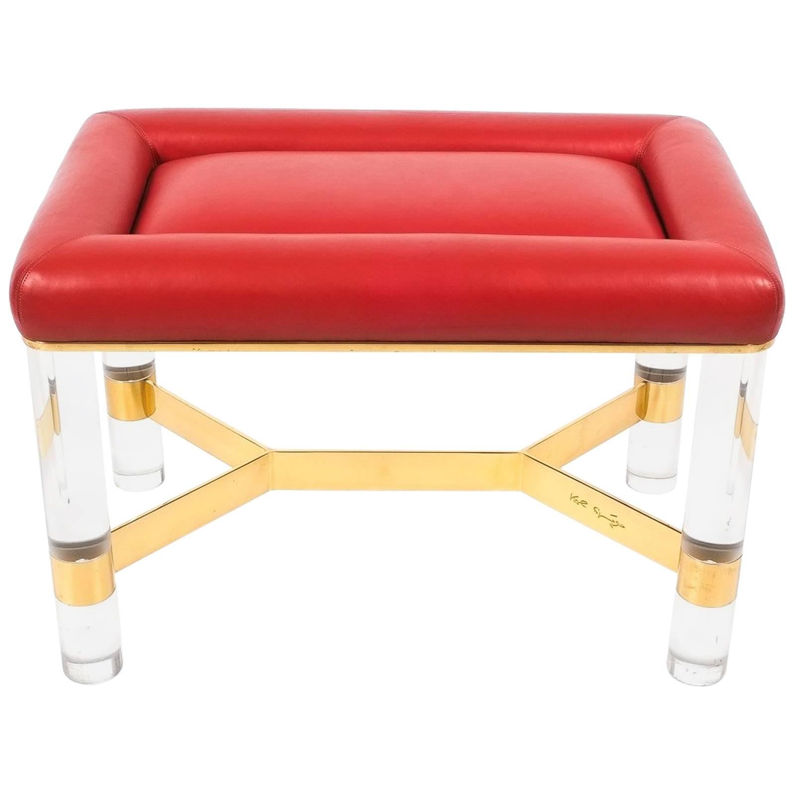Very desirable small bench or stool by Karl Springer, 1970 in excellent condition. Luxe red leather upholstery with a base made from solide cylindric Lucite legs with polished brass cross barre. Very stylish piece, signed.

