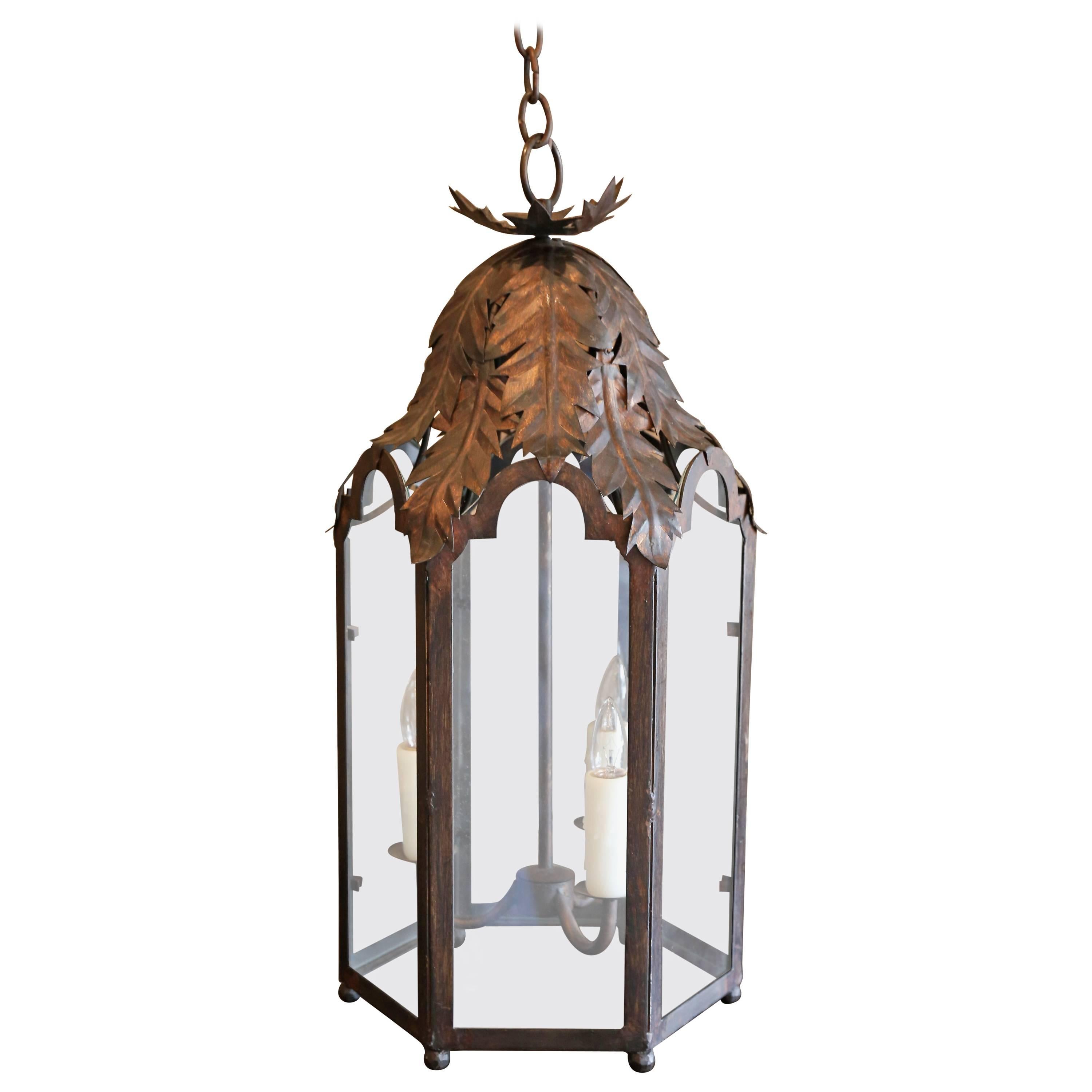 Two Italian style iron lanterns, six-sided tole and iron frames with glass panels and acanthus leaf decoration. Newly-wired for use within the USA and includes chain and canopies. Sold separately and priced $2,100 each.