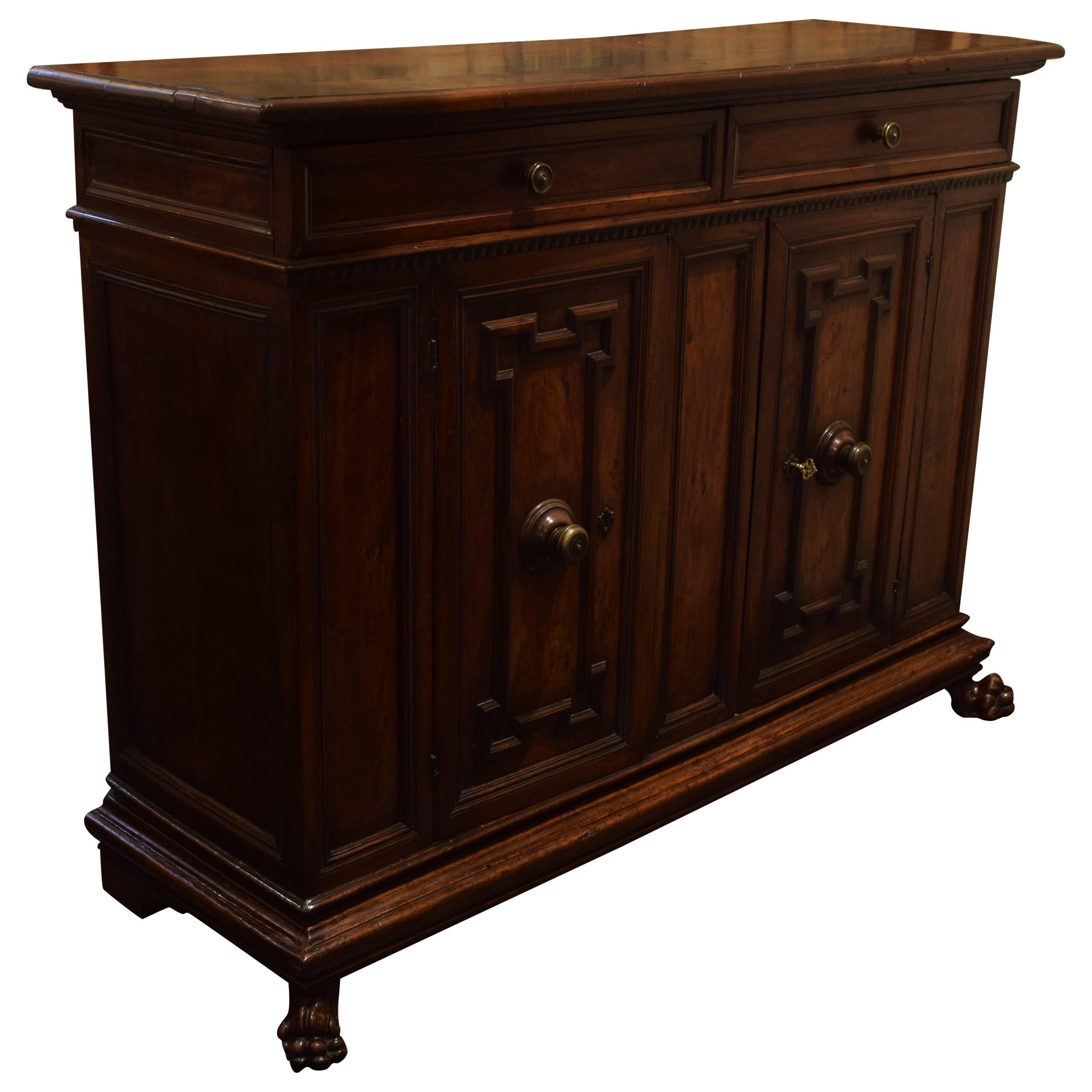 Of robust scale, the rectangular top with molded edge above a conforming case housing two drawers, the cabinet with two panelled doors opening to reveal a shelf, raised on a plinth form base and resting on large paw feet, with period bronze hardware