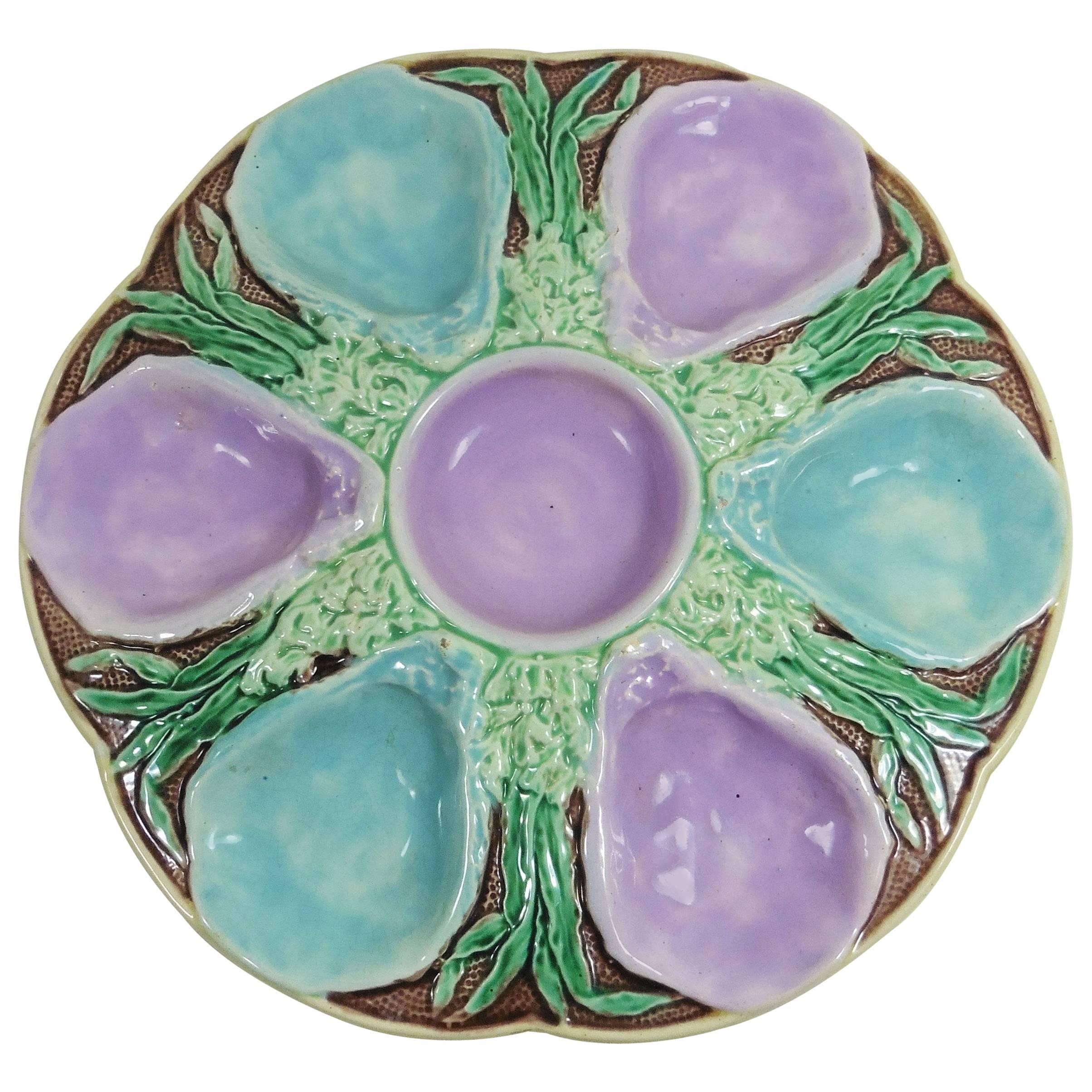 19th English Majolica six well oyster plate, the shaped circular plate with alternating turquoise and pink wells separated by seaweed against a stippled brown ground with a pink central circular well.
Reference: Page 52 