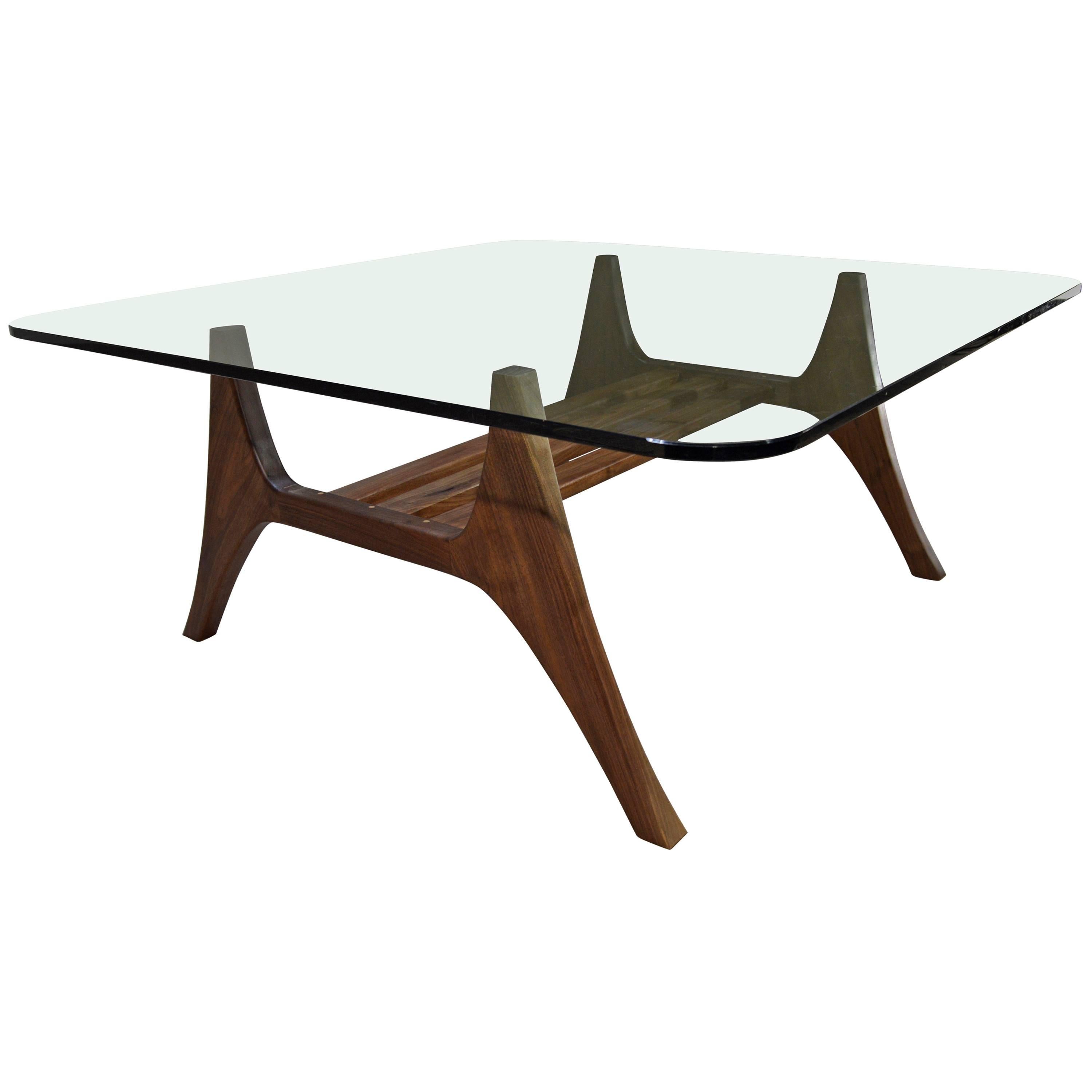 A stunning Illum Wikkelso inspired cocktail table having a sculptural solid walnut base and 1/2 inch thick glass top produced by New Hope woodworker J Pepe. 
 Vintage glass has some surface scratches. Base is in excellent condition.