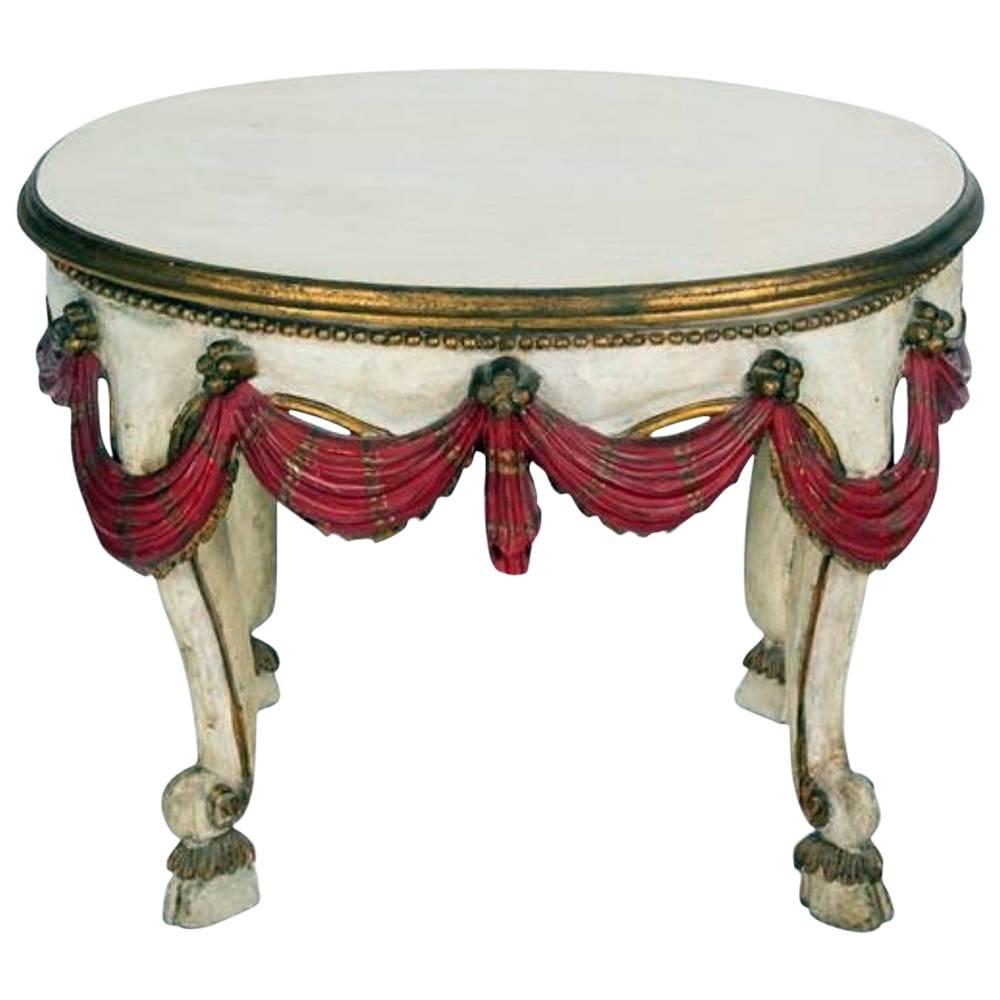 Italian painted and parcel-gilt side table, early 20th century, having an oval top over red swag decorated apron, raised on cabriole legs.
 