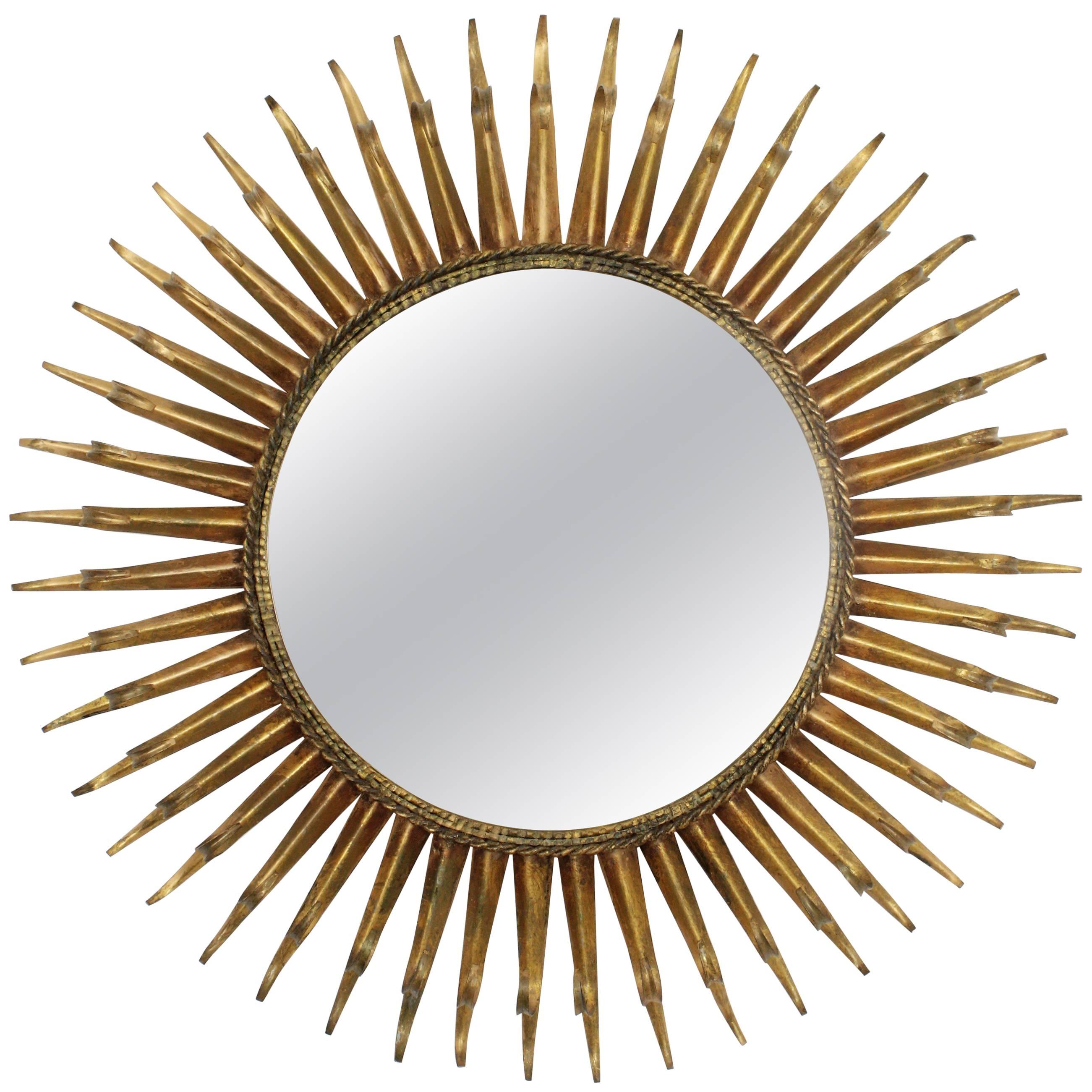 Beautiful gilt iron sunburst mirror with gold leaf patina and a highly decorative frame with eyelashed beams,
France, 1960s.

Measures: Glass surface 39cm diameter.

Available a huge collection of sunburst mirrors and other kind of mirrors.